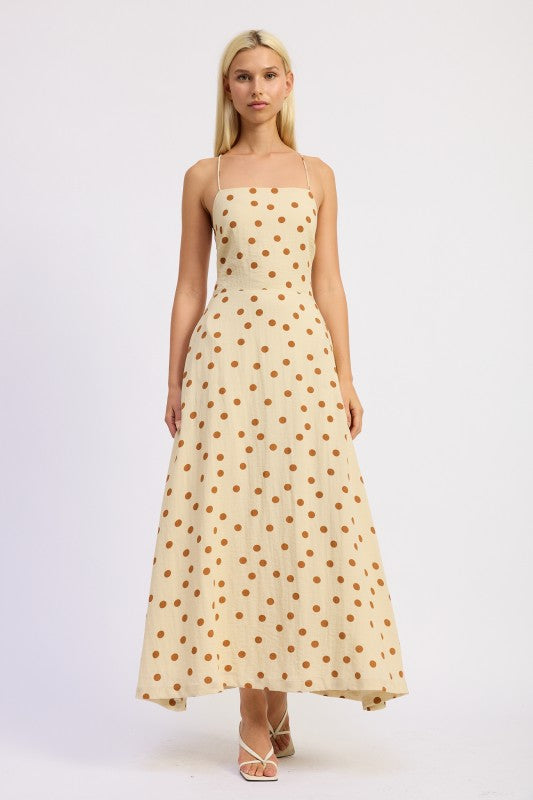 Model wearing a butter cream maxi dress with caramel polka dots and a straight neckline.