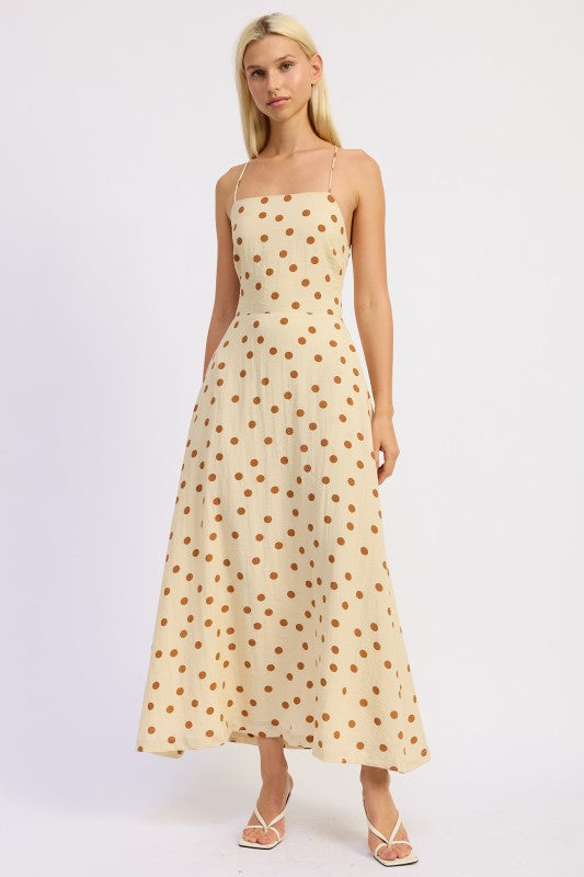 Model wearing a butter cream maxi dress with caramel polka dots and a straight neckline.