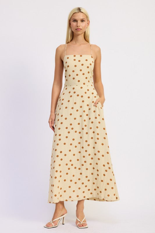 Model wearing a butter cream maxi dress with caramel polka dots and a straight neckline.