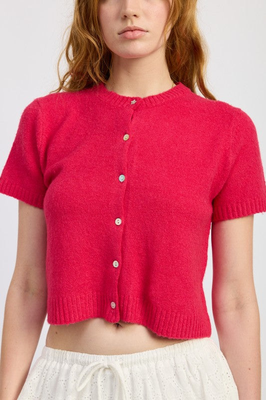 Close-up of fuchsia knit cardigan showing button detail and ribbed texture