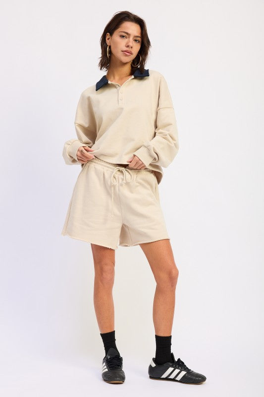 Ivory relaxed long sleeve collared top styled with matching drawstring shorts and sneakers