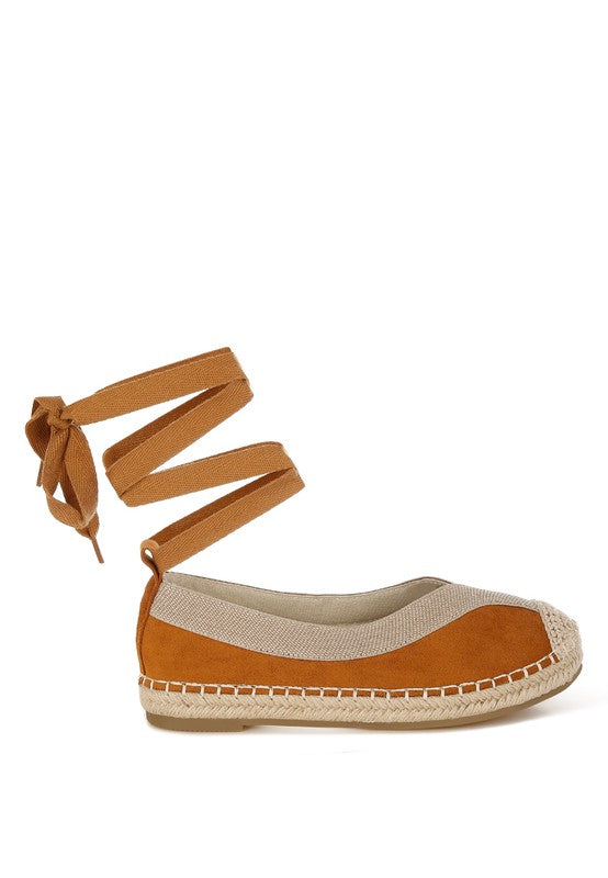 Tan espadrille flat with beige canvas trim and ankle wrap ribbon, side profile