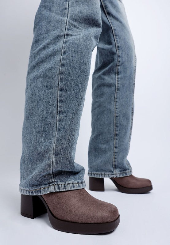 Taupe shoes worn with blue jeans on a white background