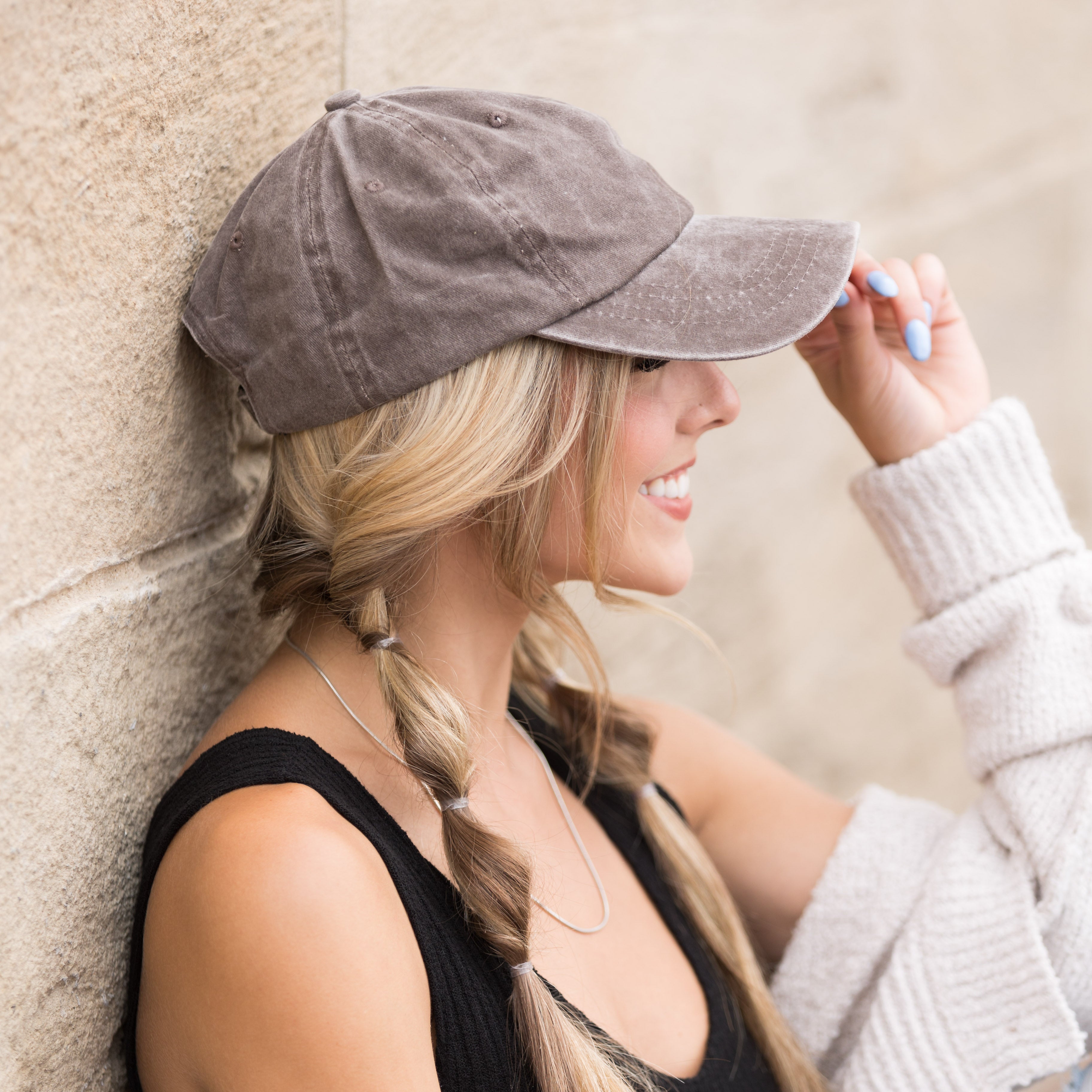 Woman wearing a cotton twill gray cap against a stone wall