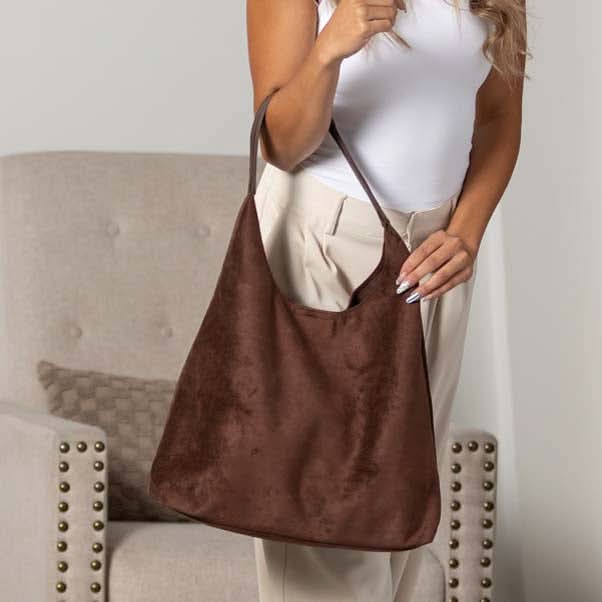 Mocha suede-look hobo bag worn over the shoulder with vegan leather strap.