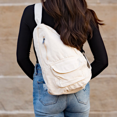 Person wearing a cream canvas backpack with a blurred background