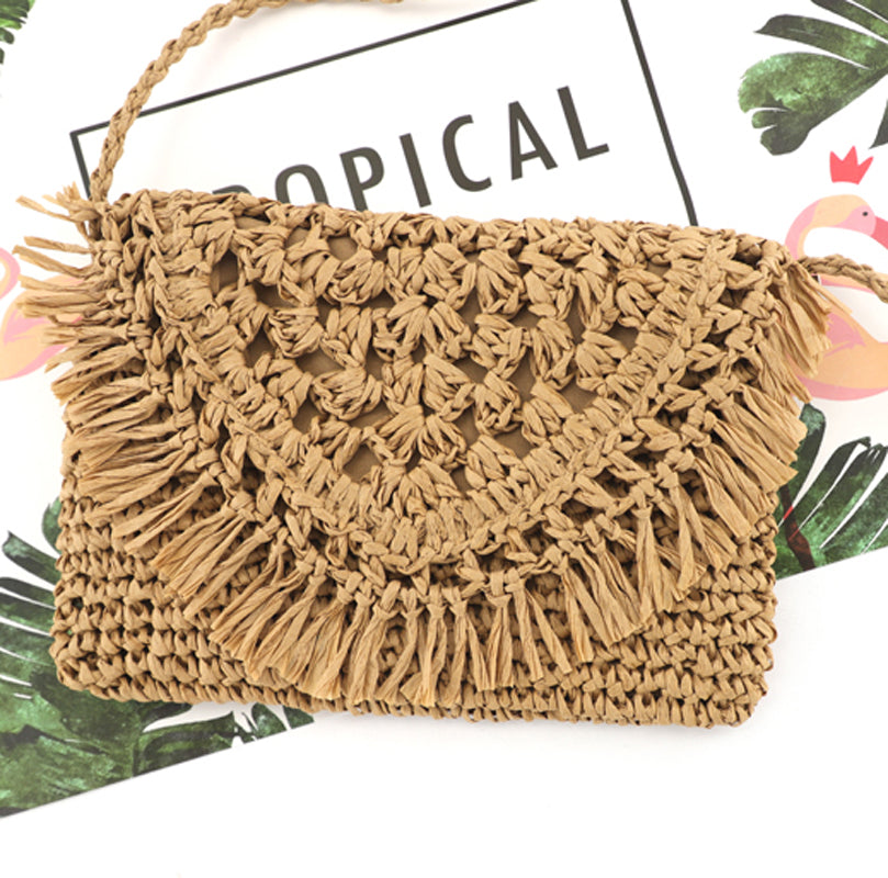 close up of khaki woven straw crossbody with fringe flap detail, styled with a white blouse and denim shorts-AVAH