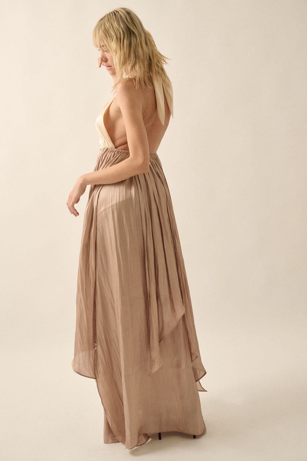 Back view of model wearing halter maxi dress with self-tie straps and open back, showing taupe satin skirt draping to floor