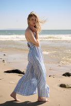 Side view of model strolling in Mediterranean print jumpsuit with ocean breeze movement