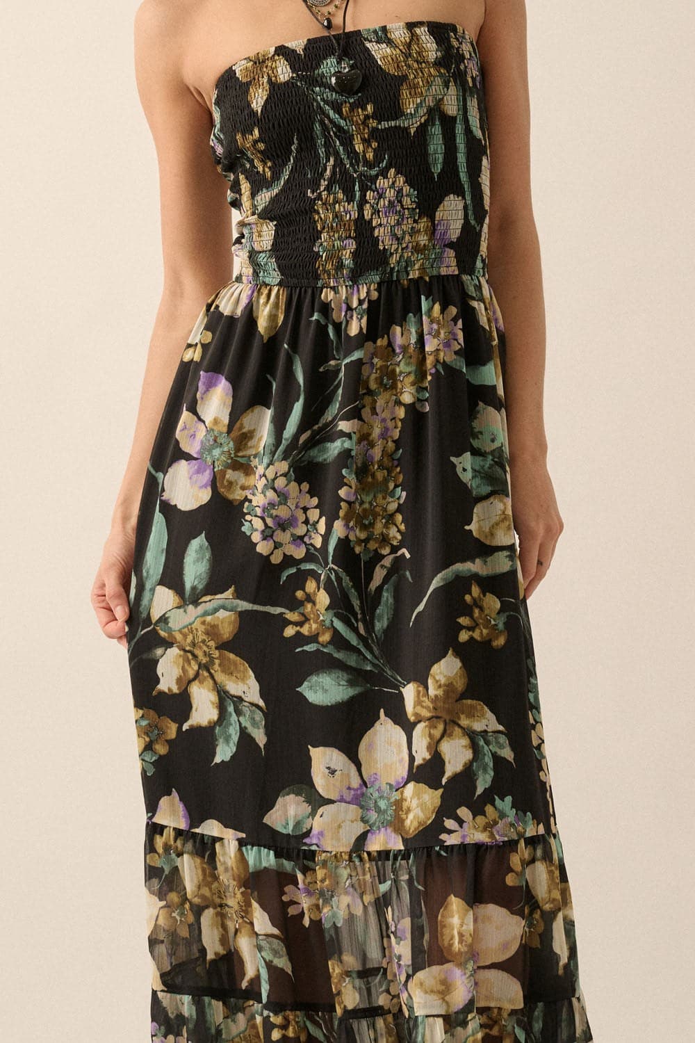 Close-up of smocked bodice and floral print detail on black chiffon fabric of the maxi dress