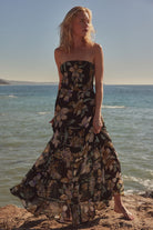 Woman wearing a strapless black floral maxi dress with smocked bodice and tiered skirt on the beach-AVAH