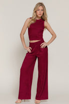 Model wearing a red sleeveless top and wide-leg pants on a plain background