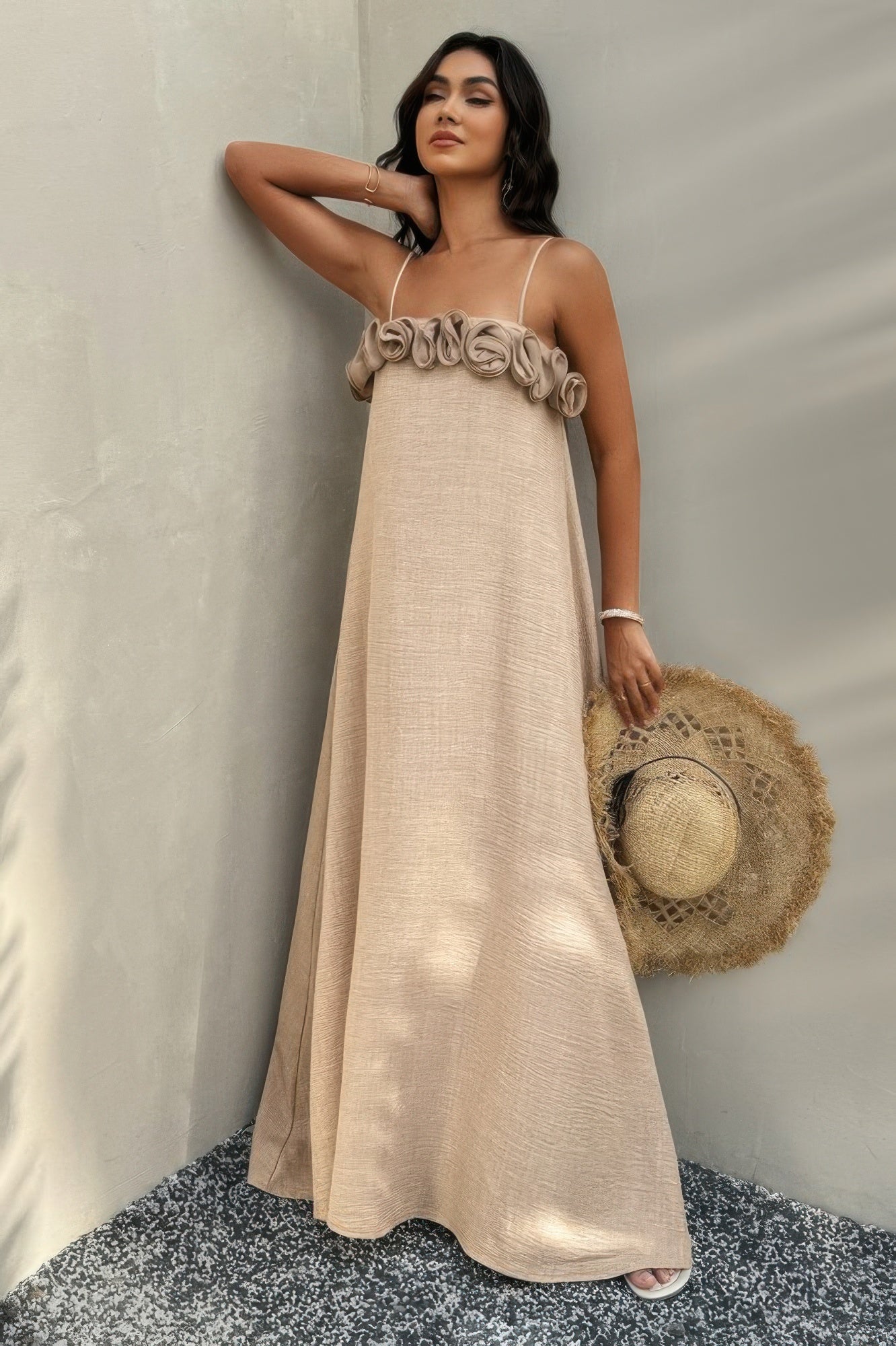 Full view of model in petal trim maxi dress holding a straw hat with soft light and shadows
