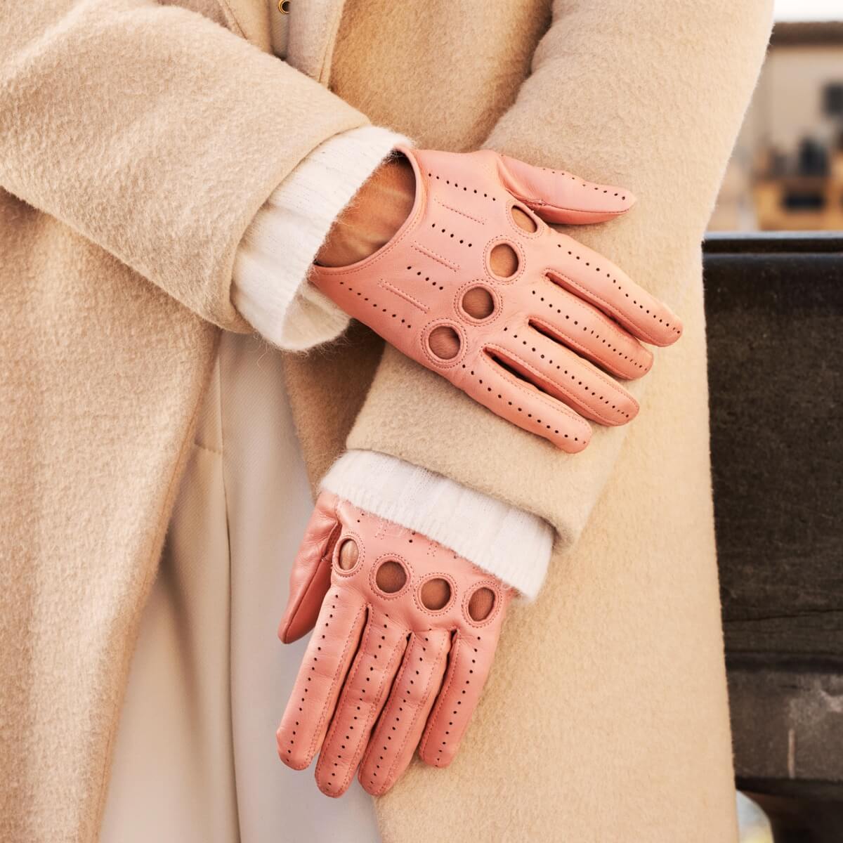 Person wearing pink leather gloves with a beige coat.