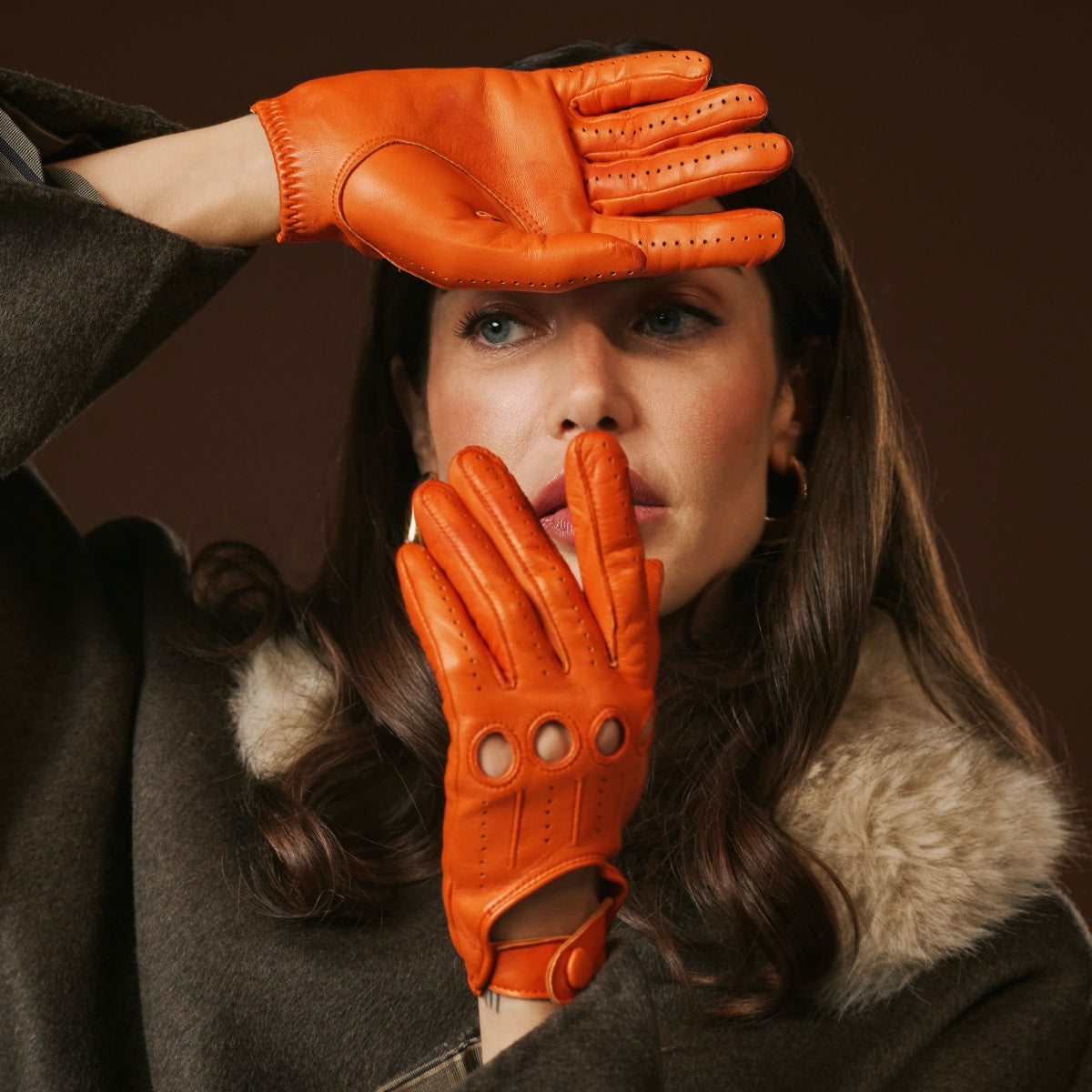 Person wearing orange leather gloves with a dark background