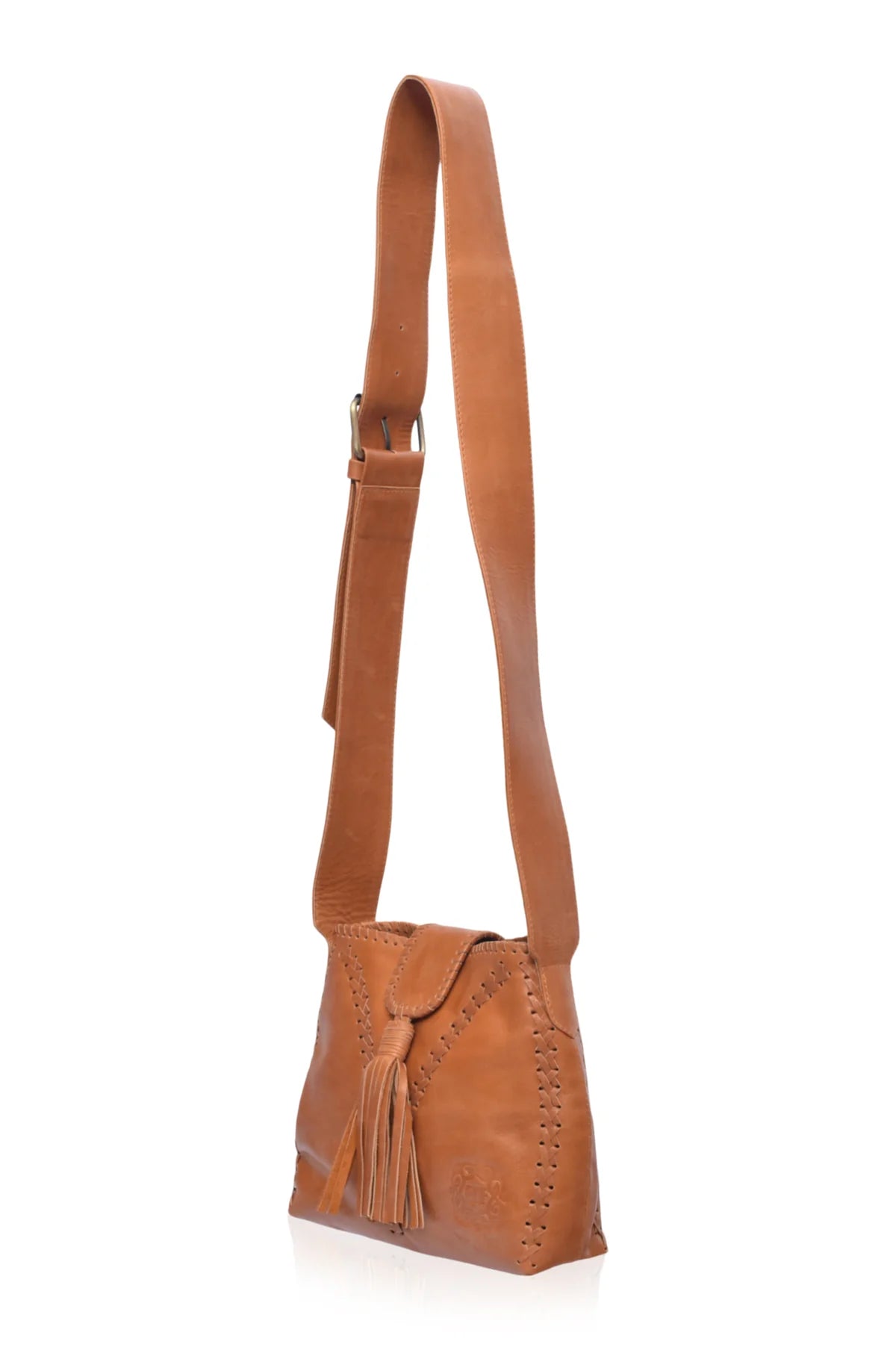 A tan leather crossbody bag with a long adjustable strap, a front flap with a tassel, and decorative stitching on the sides, shown against a plain white background.