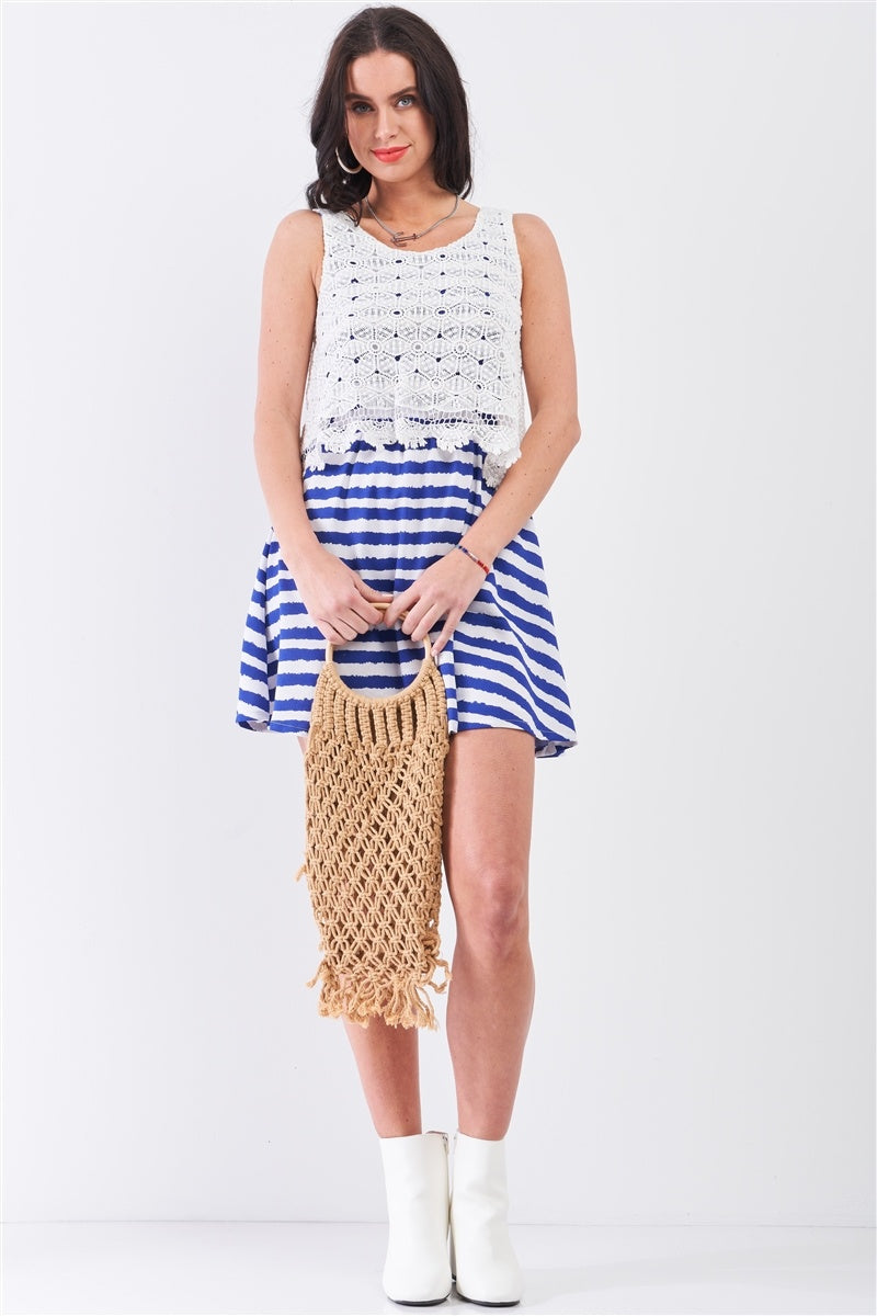 Model holding woven tote wearing blue striped sleeveless mini dress with crochet lace top