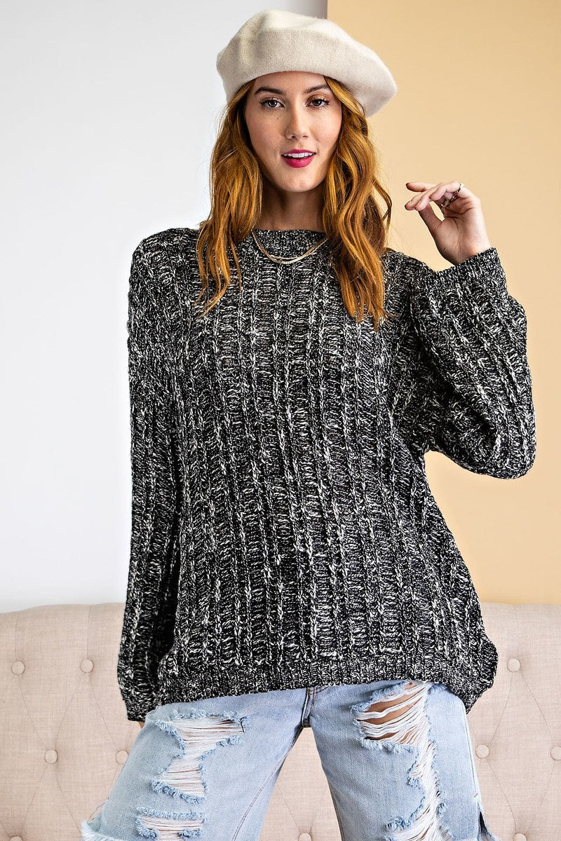 Model wearing a black and white marled rib knit sweater with a relaxed fit and crew neckline.
