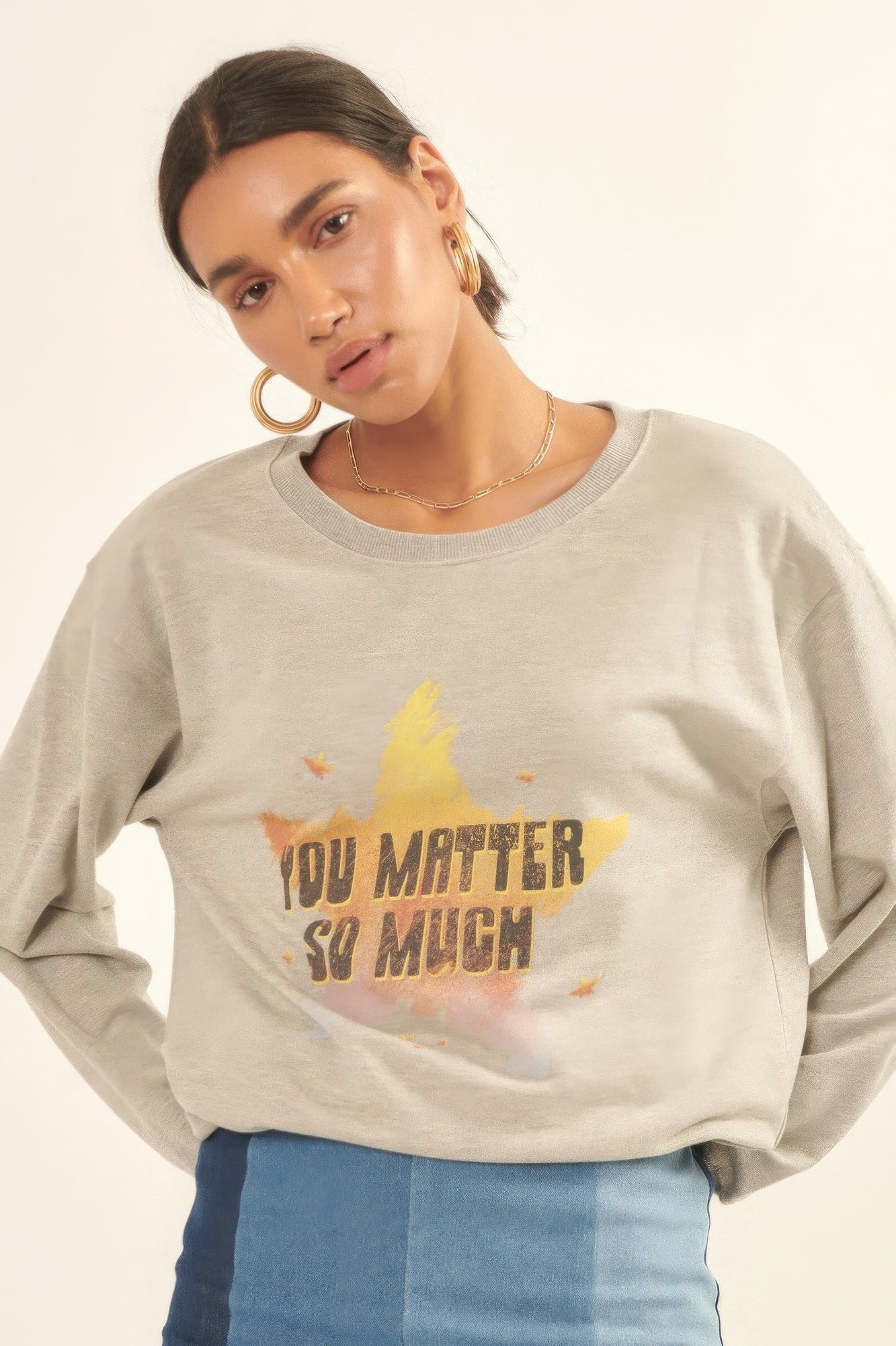 Close-up of Radiance Reminder Graphic Sweatshirt with yellow and orange star design and bold lettering