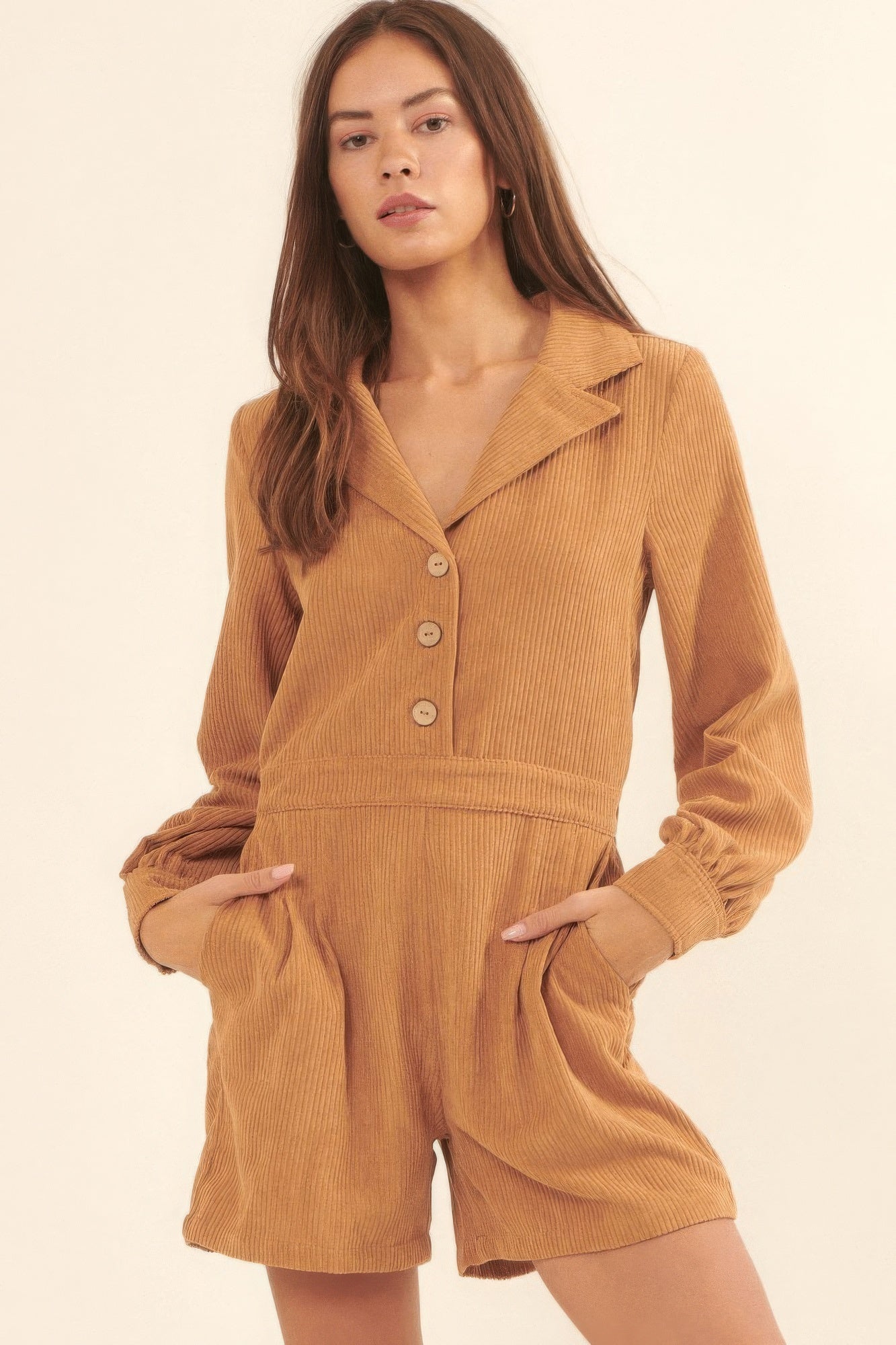 Model wearing a tan corduroy long sleeve romper with button-front detail, collared neckline, and side pockets-AVAH