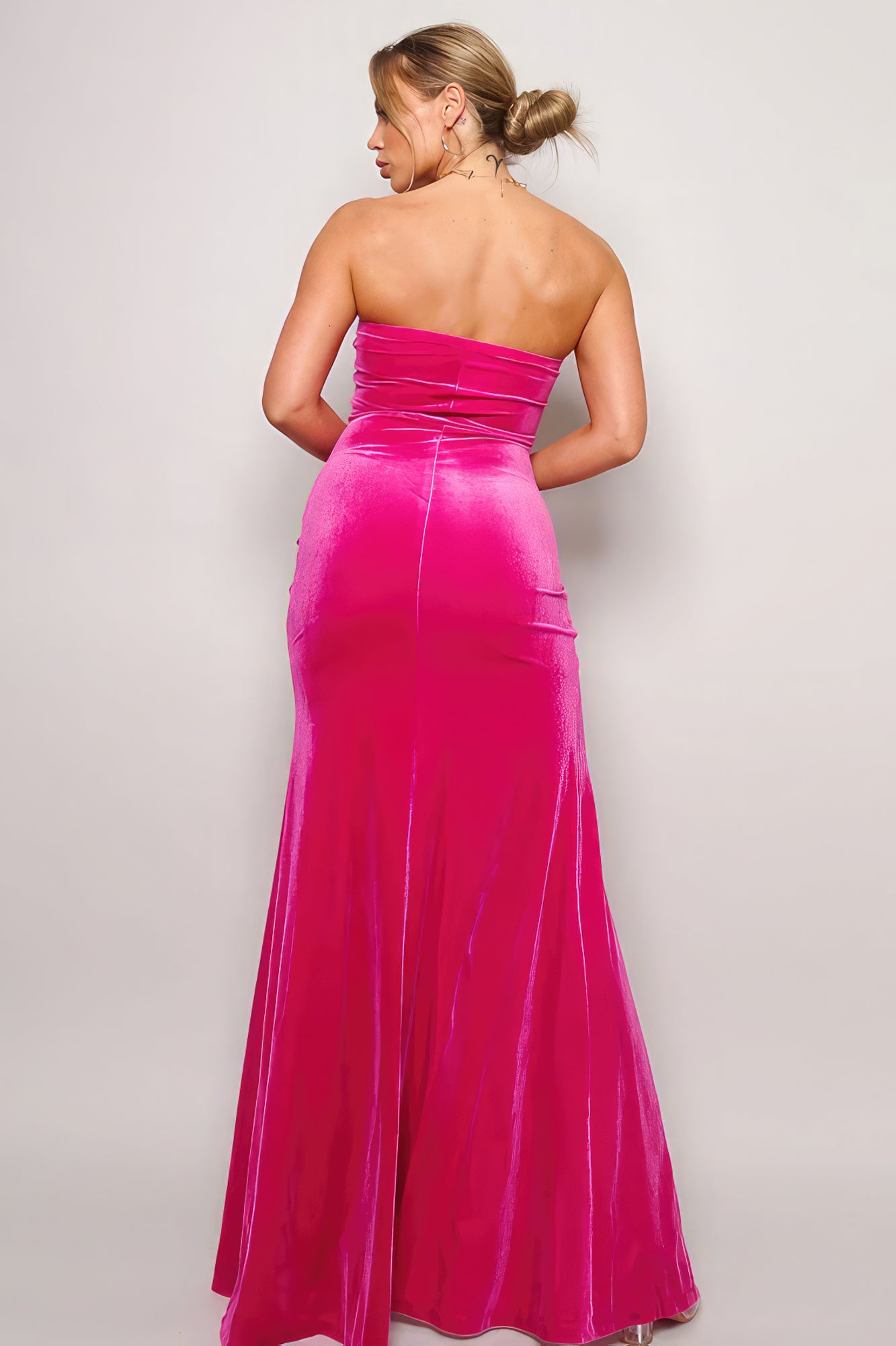 Back view of a fuchsia strapless maxi dress with fitted silhouette and floor length hem.