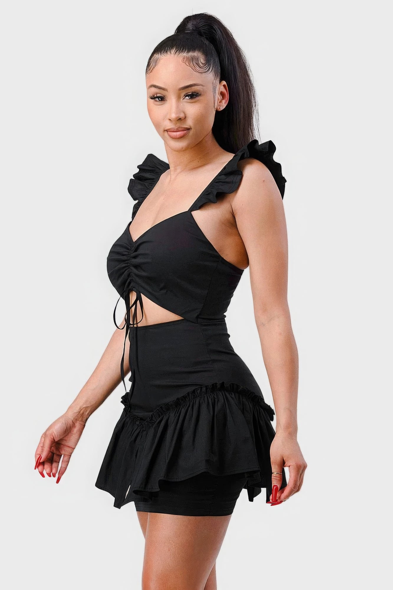 Side view of black ruched mini dress with front tie detail and ruffled skirt