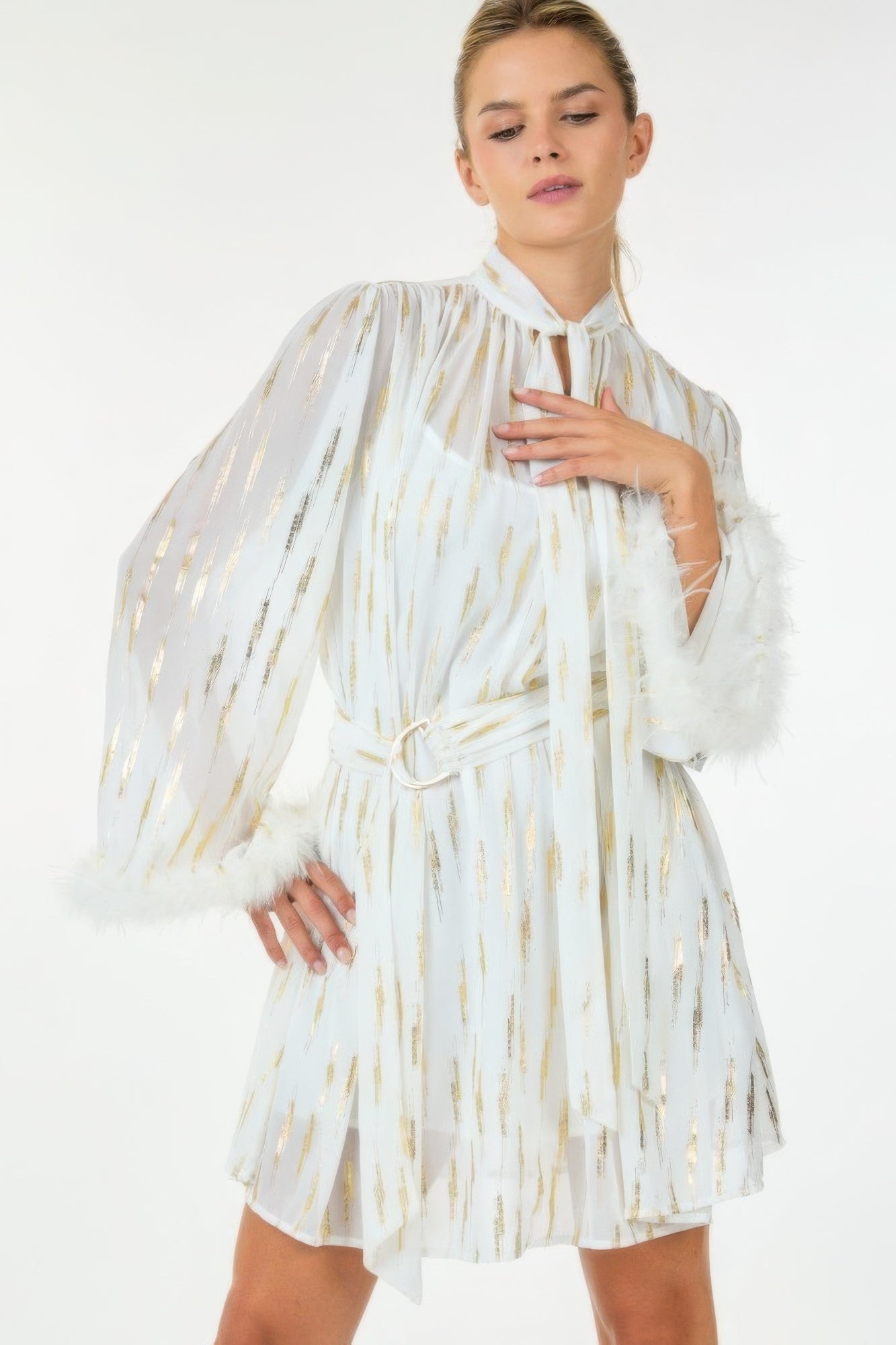 Front angled view of white metallic mini dress with feather cuffs and belted waist.