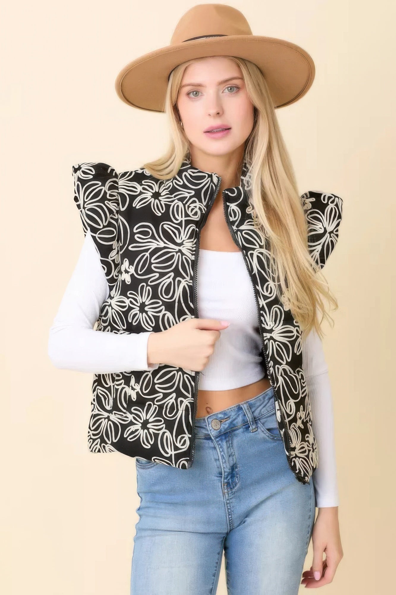 Woman wearing black floral embroidered puffer vest with ruffle shoulders front view