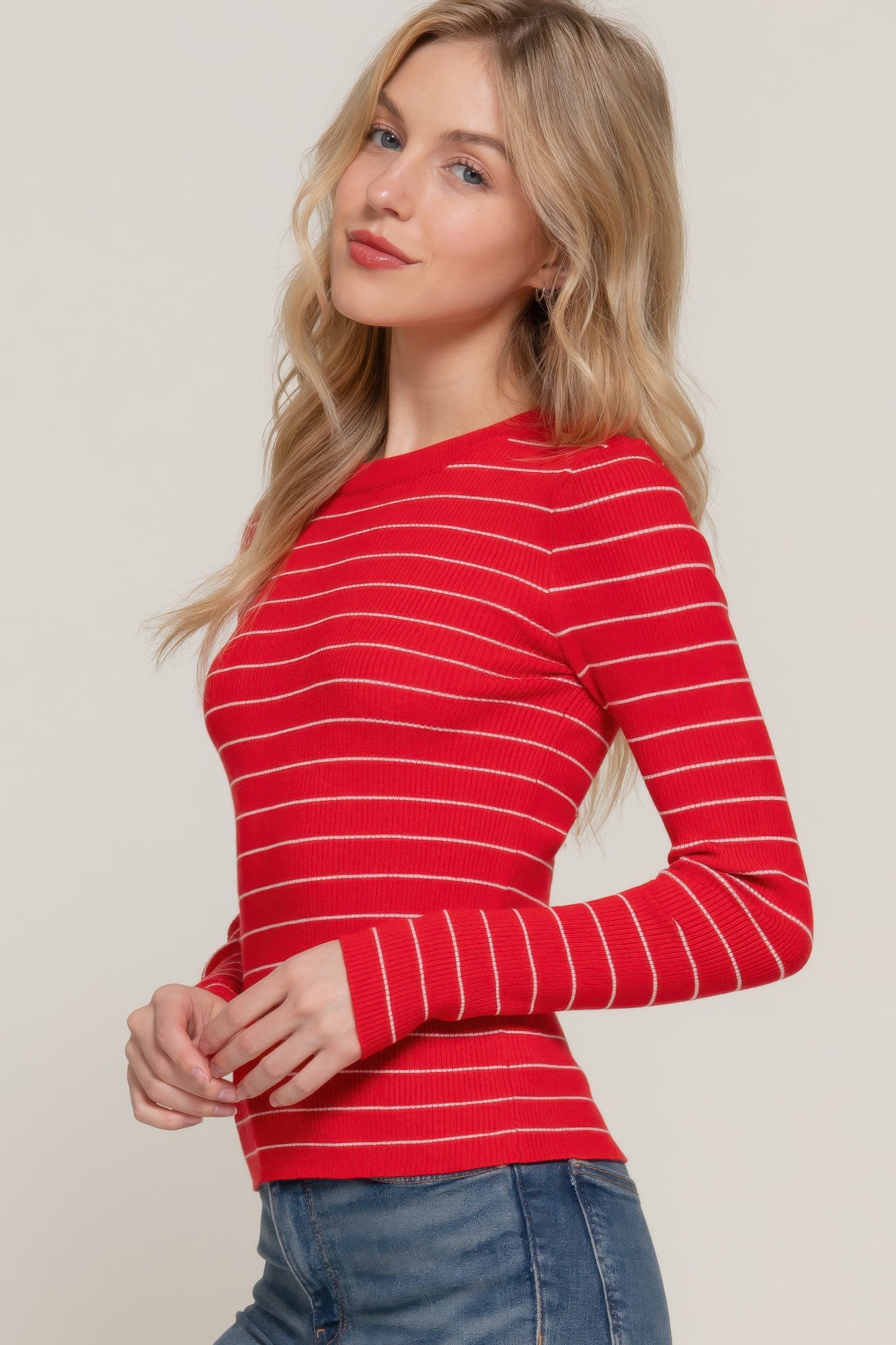Close-up of the red ribbed long sleeve top with white stripes, styled with blue jeans.