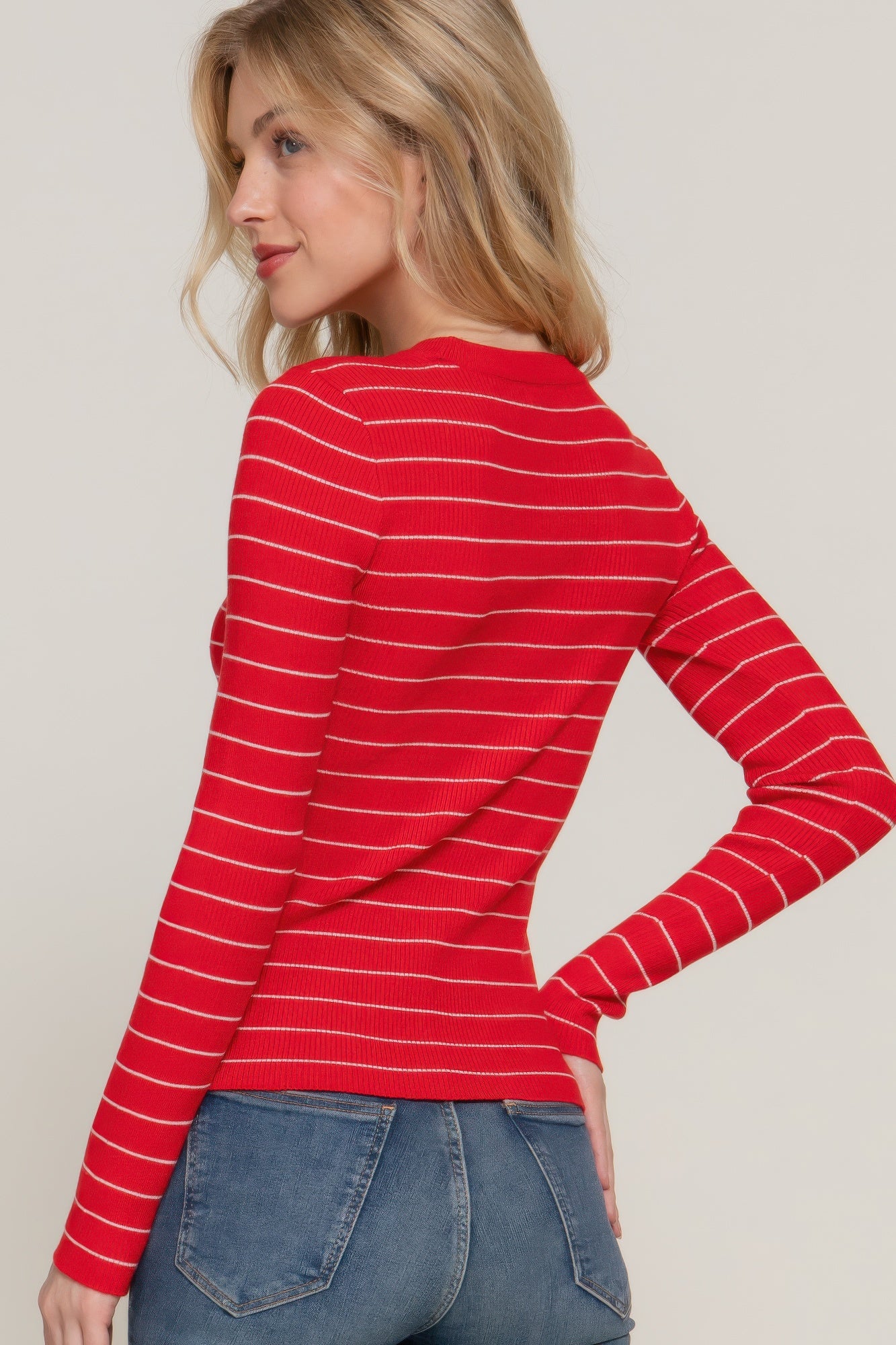 Model posing in a red striped ribbed knit top and blue jeans, showing the fitted silhouette-back view