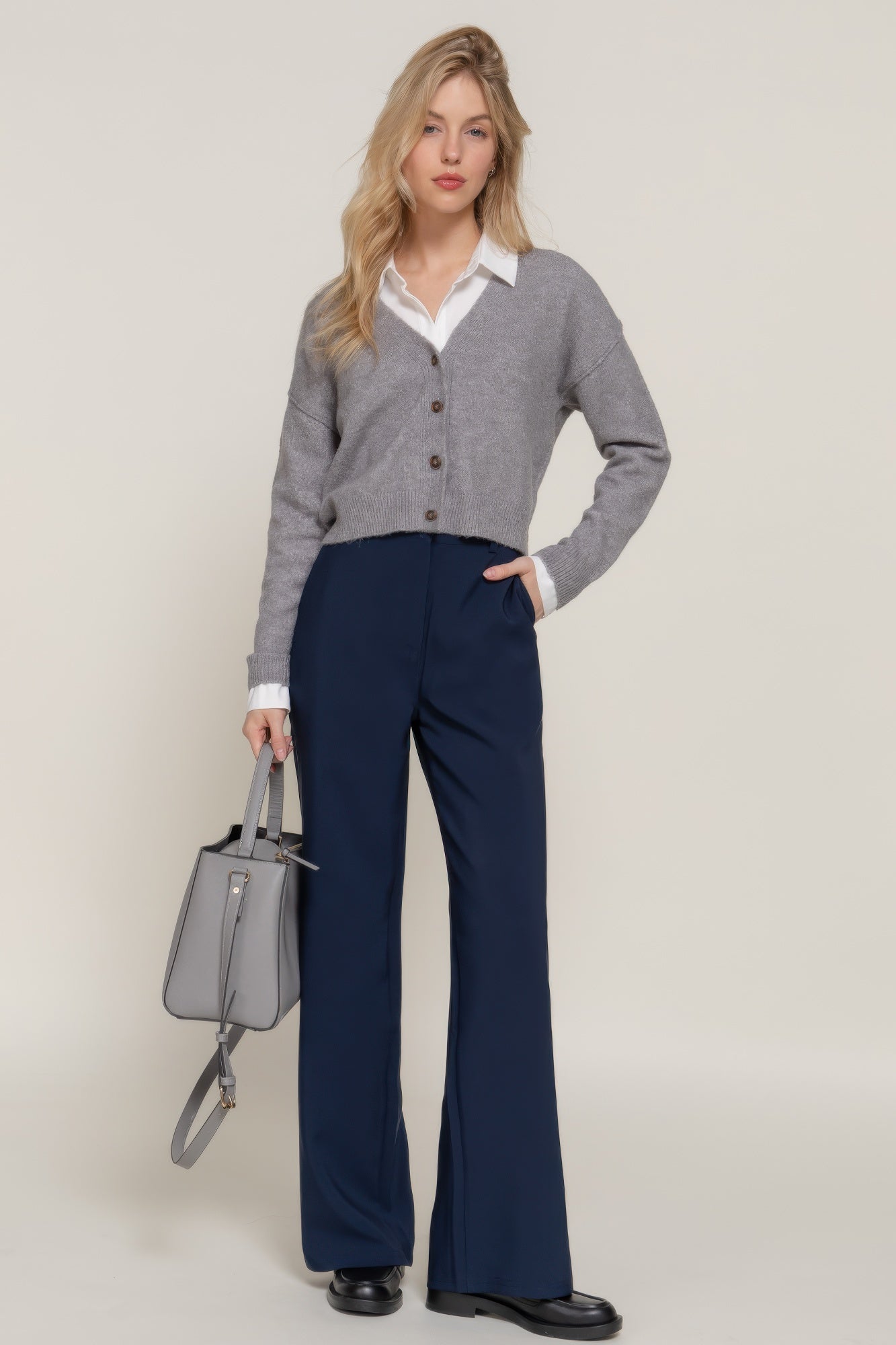 Model in navy straight-leg pants paired with a grey cardigan and white shirt