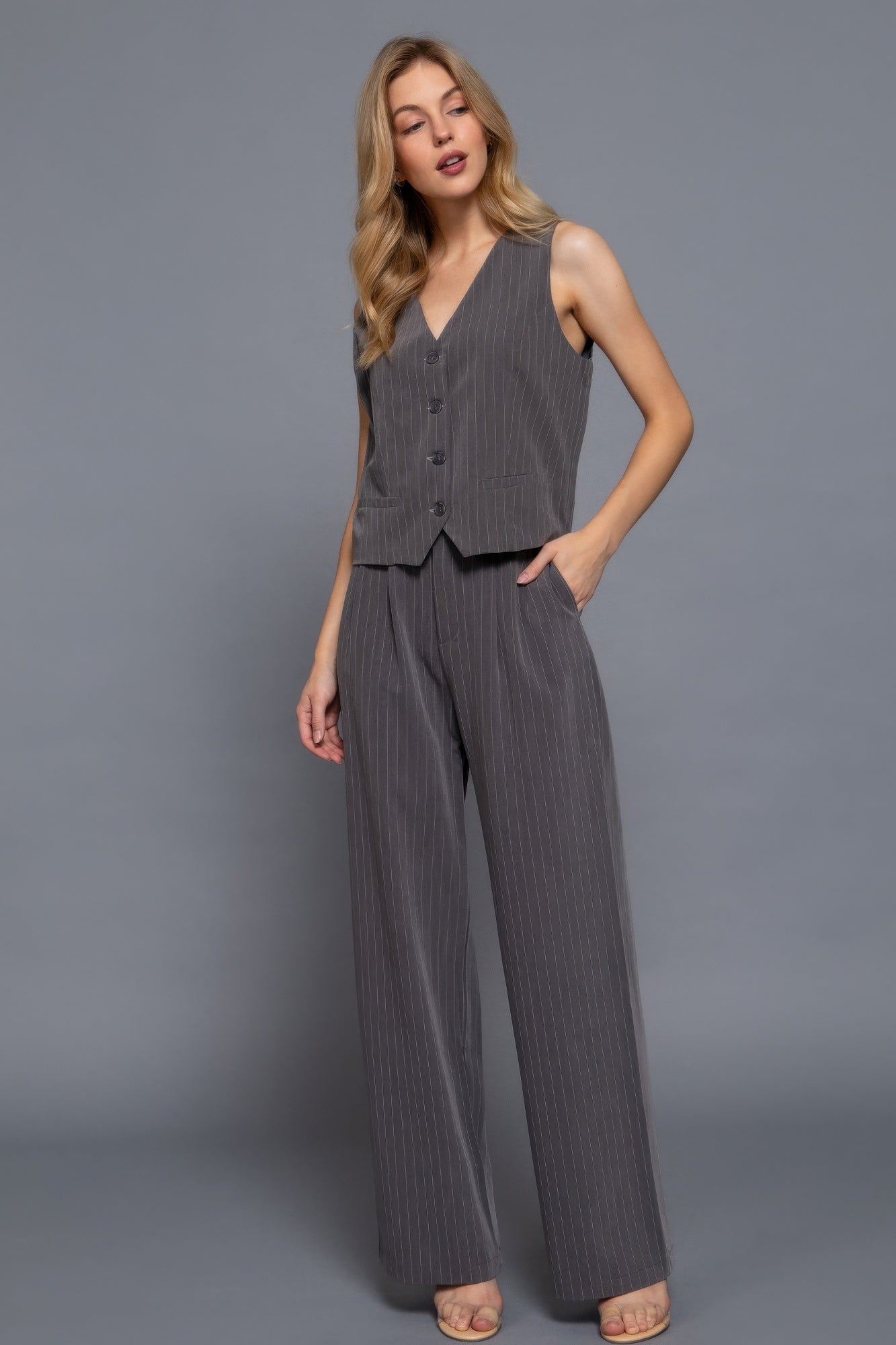 Model wearing high-waisted charcoal pinstripe wide-leg pants with tailored fit and button closure, styled with matching vest and nude heels-AVAH
