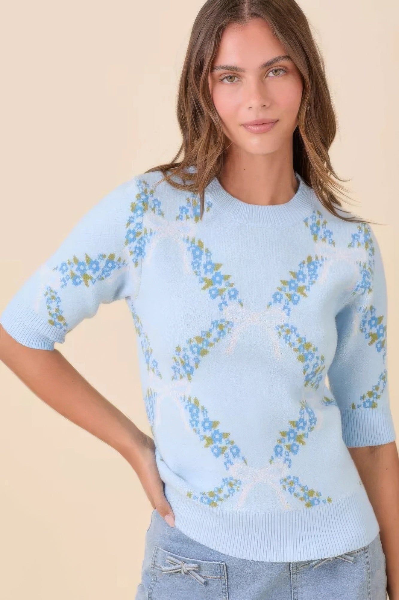 Model wearing light blue floral knit sweater, angled front view.