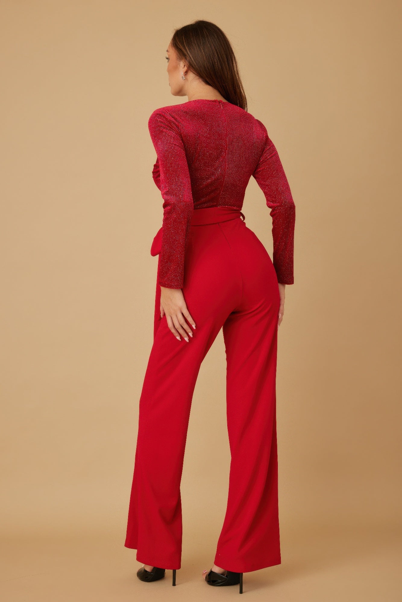 Angle back view of red long sleeve jumpsuit with waist tie