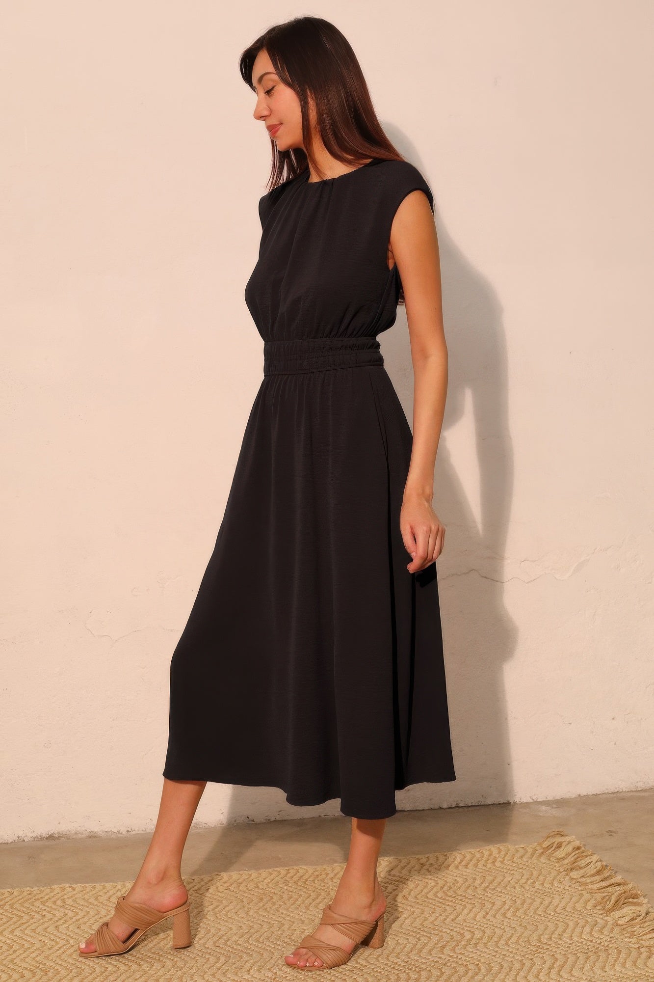 Side view of black flowy midi dress with pockets