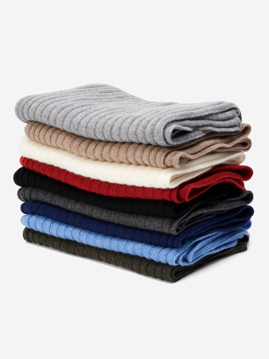 Stack of folded cashmere scarves in various colors on a white background