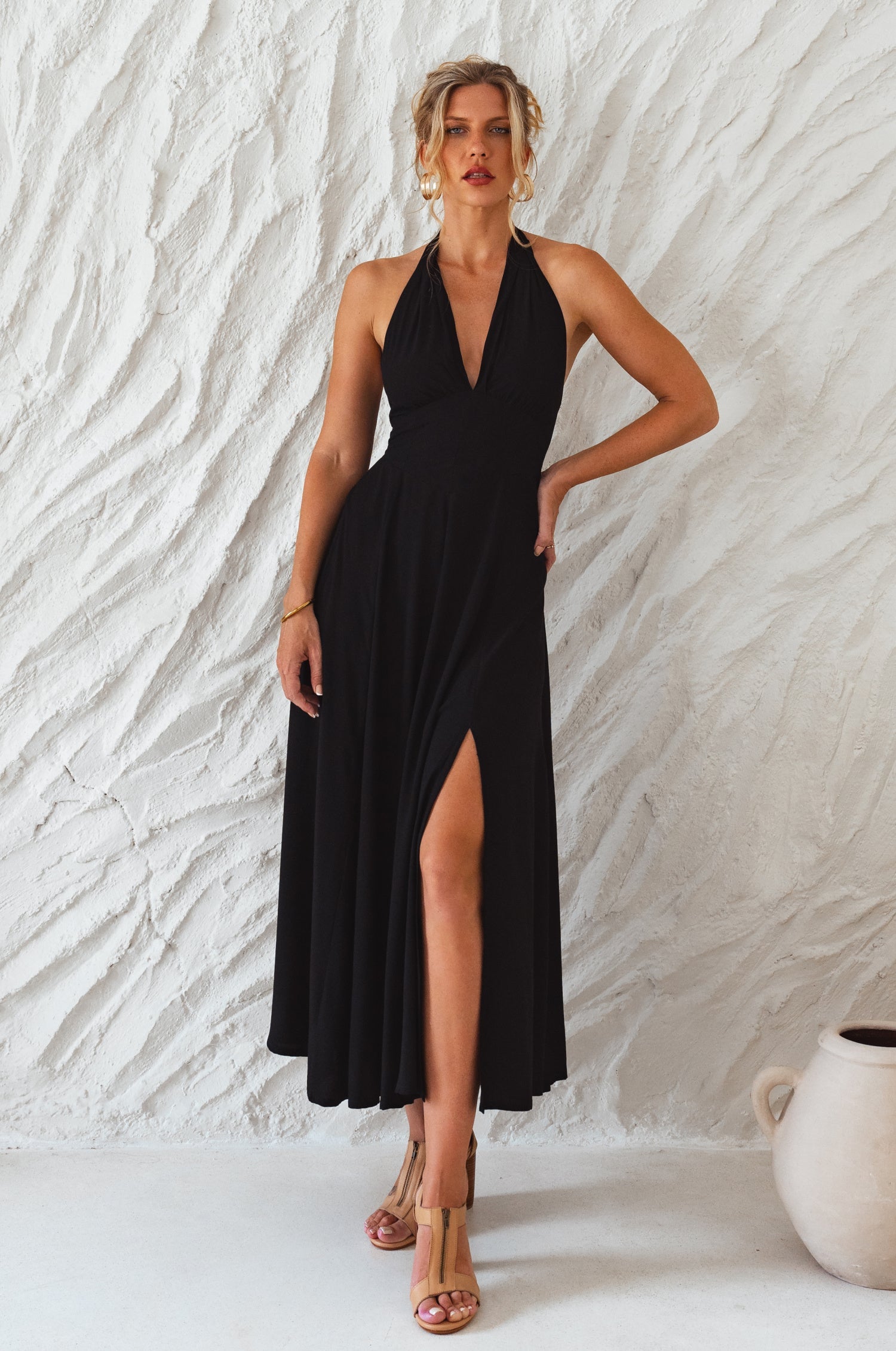 Woman wearing a black soft rayon maxi dress with halter neckline, smocked back, and fitted bodice, on a white background, front view