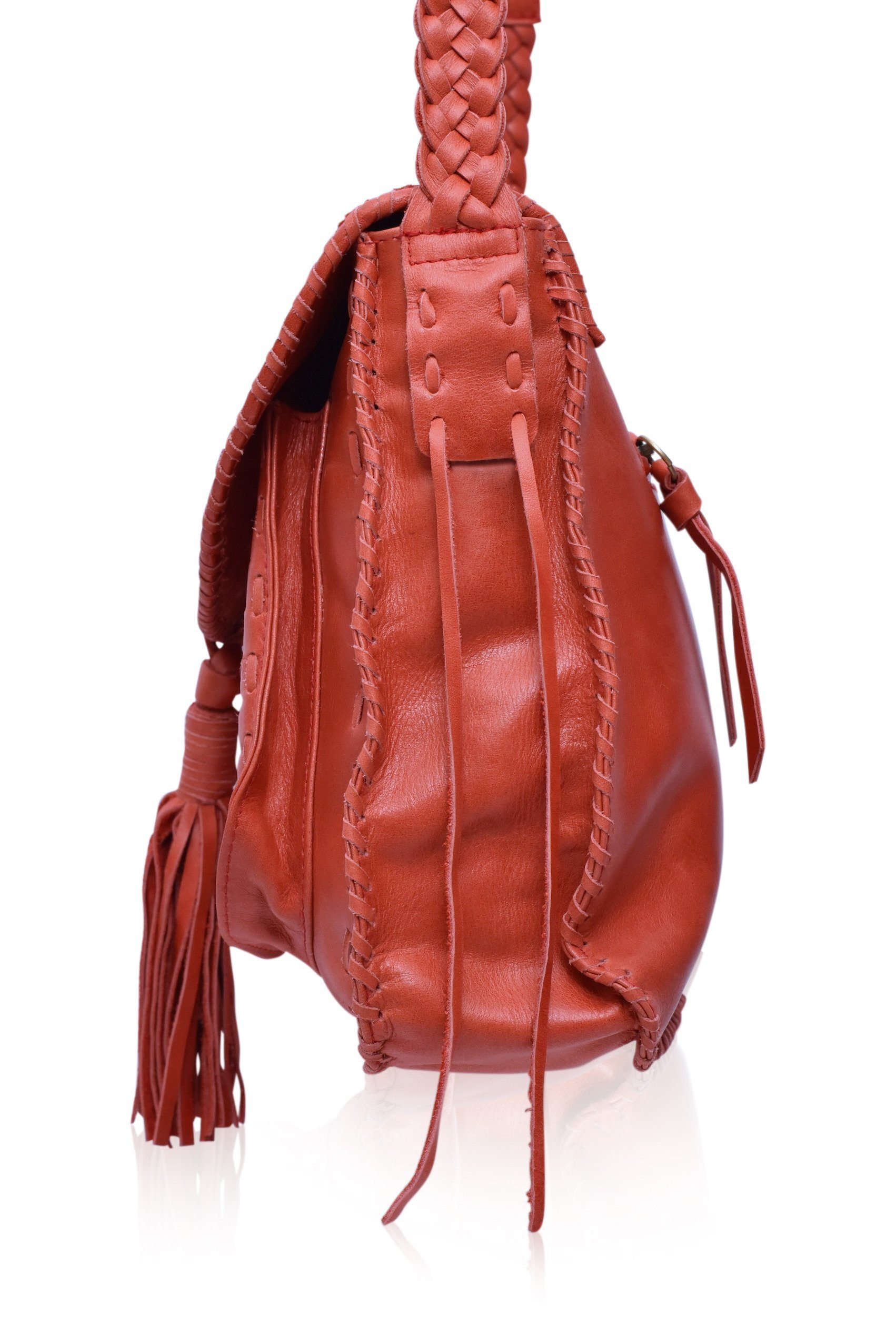 Close up of a red woven handbag with tassels on a white background, side view
