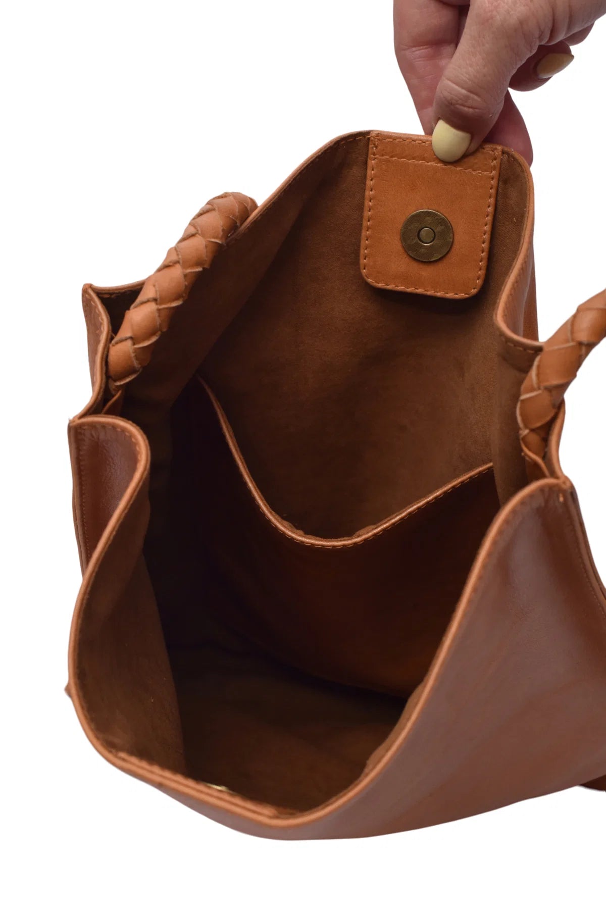 Interior view of tan leather handbag with braided handles held by a hand on a white background