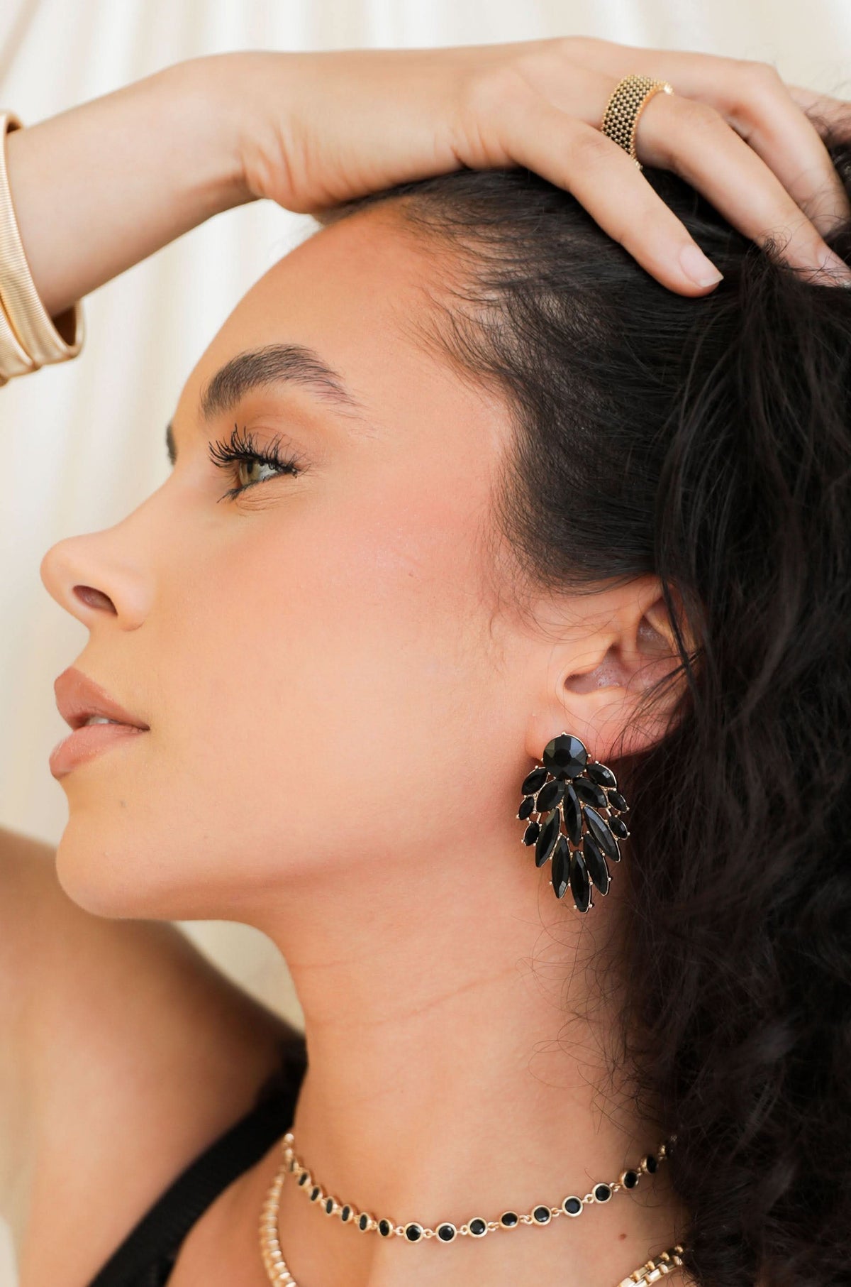 Woman wearing black crystal cluster drop earrings indoors.