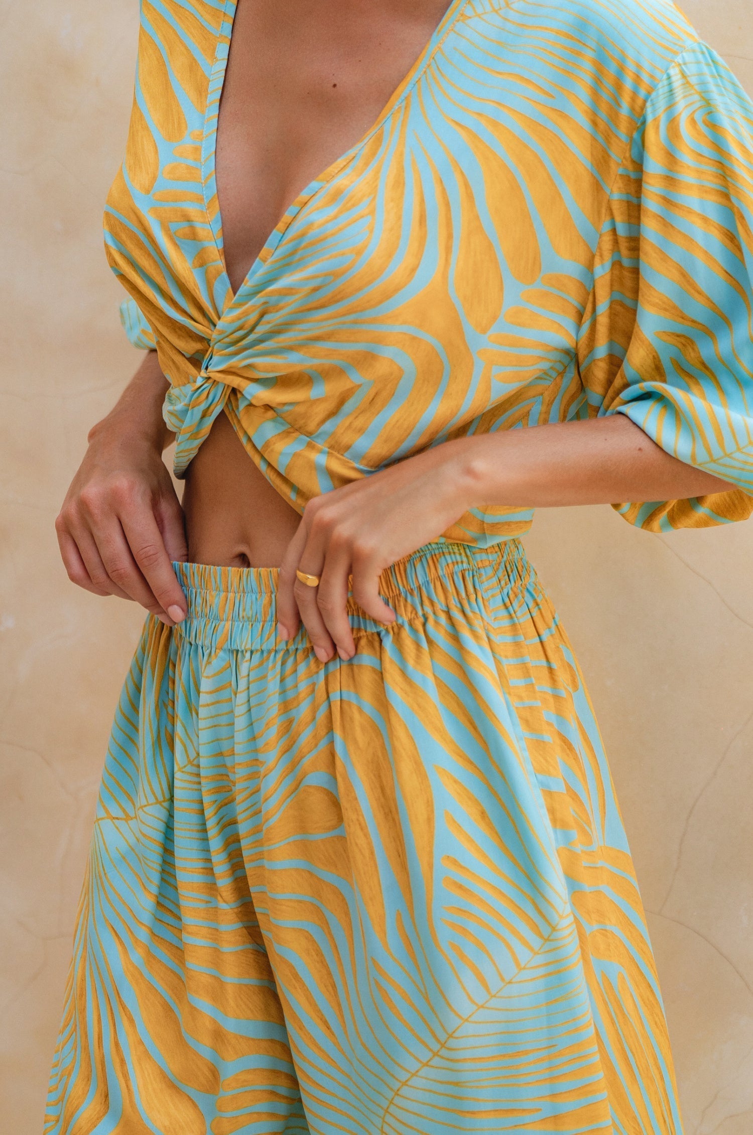 Person wearing a yellow and blue patterned outfit against a beige background