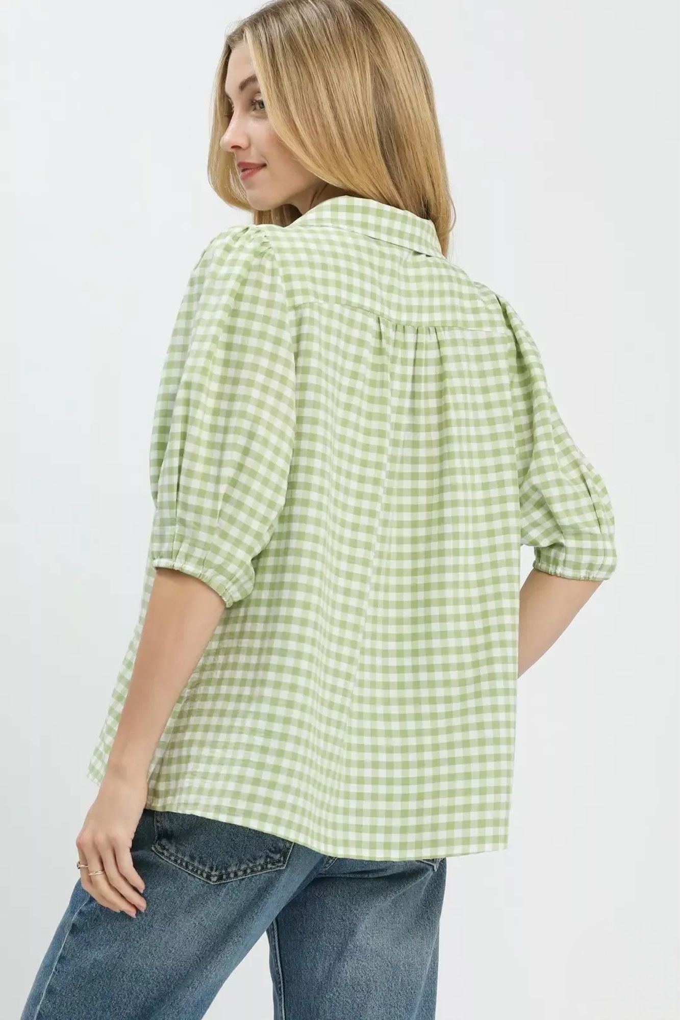Woman wearing a green checkered shirt and blue jeans on a white background