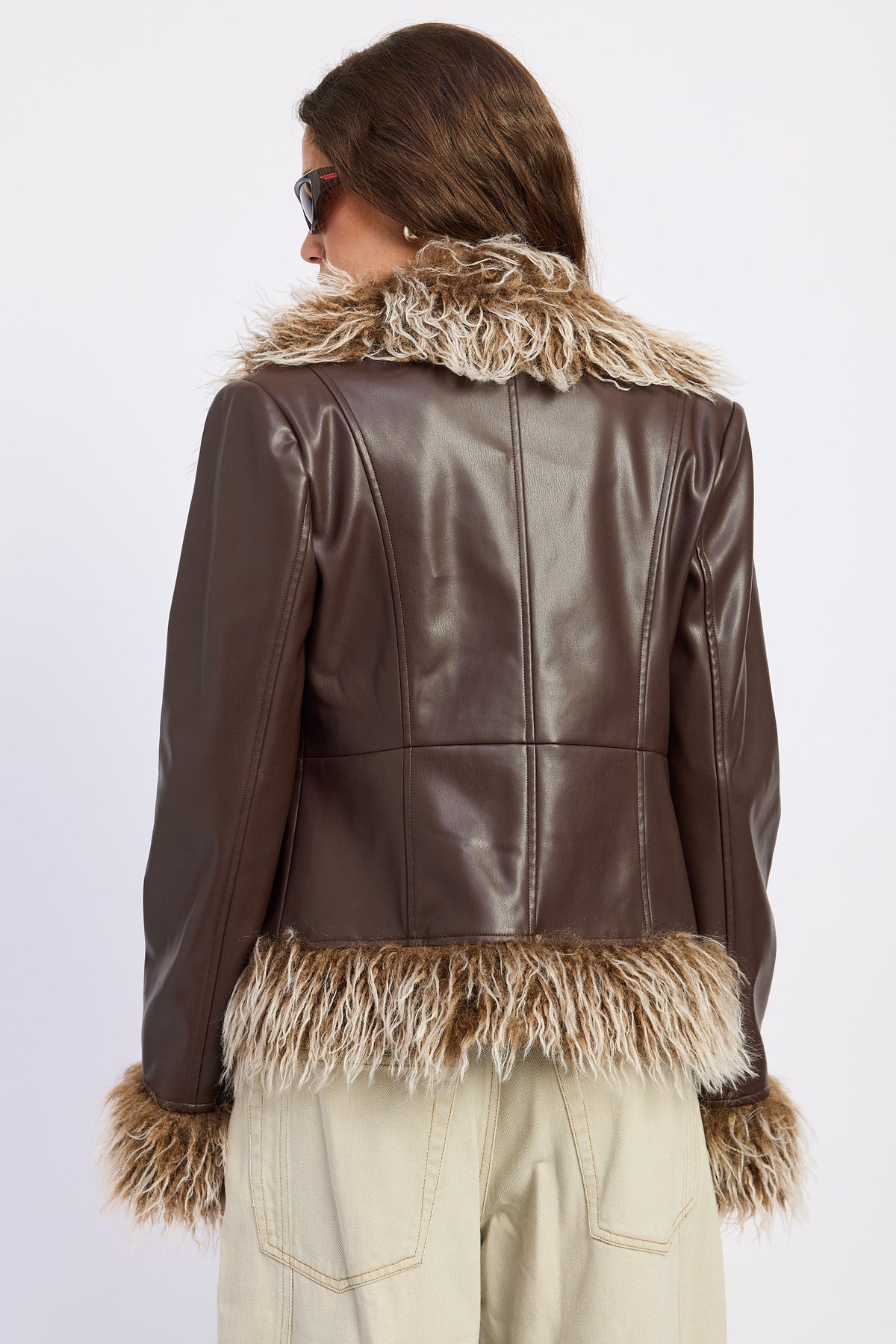Back view of brown faux leather jacket showing structured seam detailing and contrasting shaggy faux fur trim.