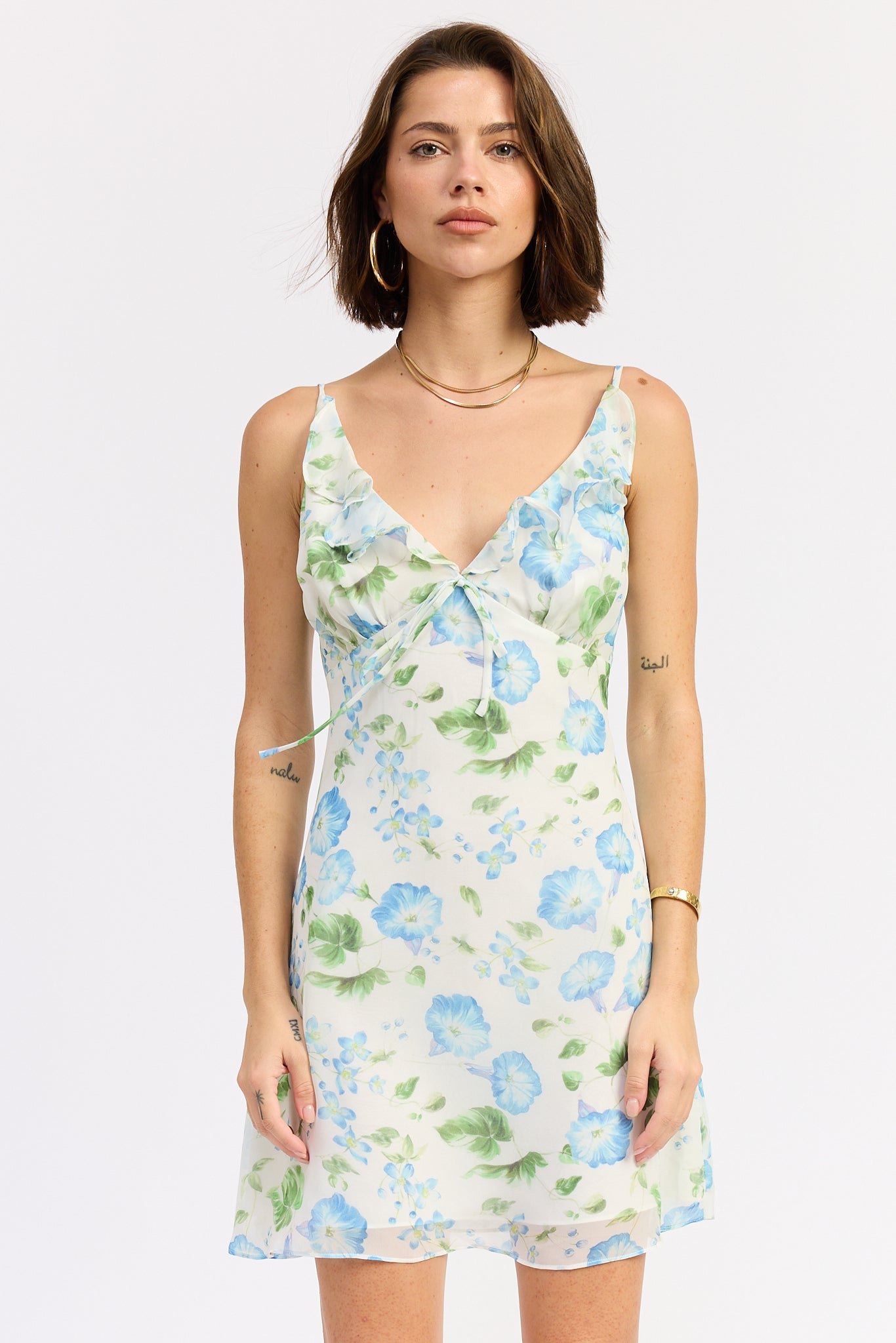 Woman wearing a floral dress on a white background, front view