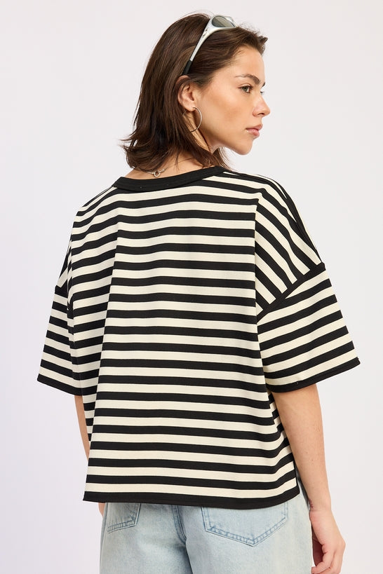 Woman wearing a black and white striped shirt with light blue jeans on a plain background back view
