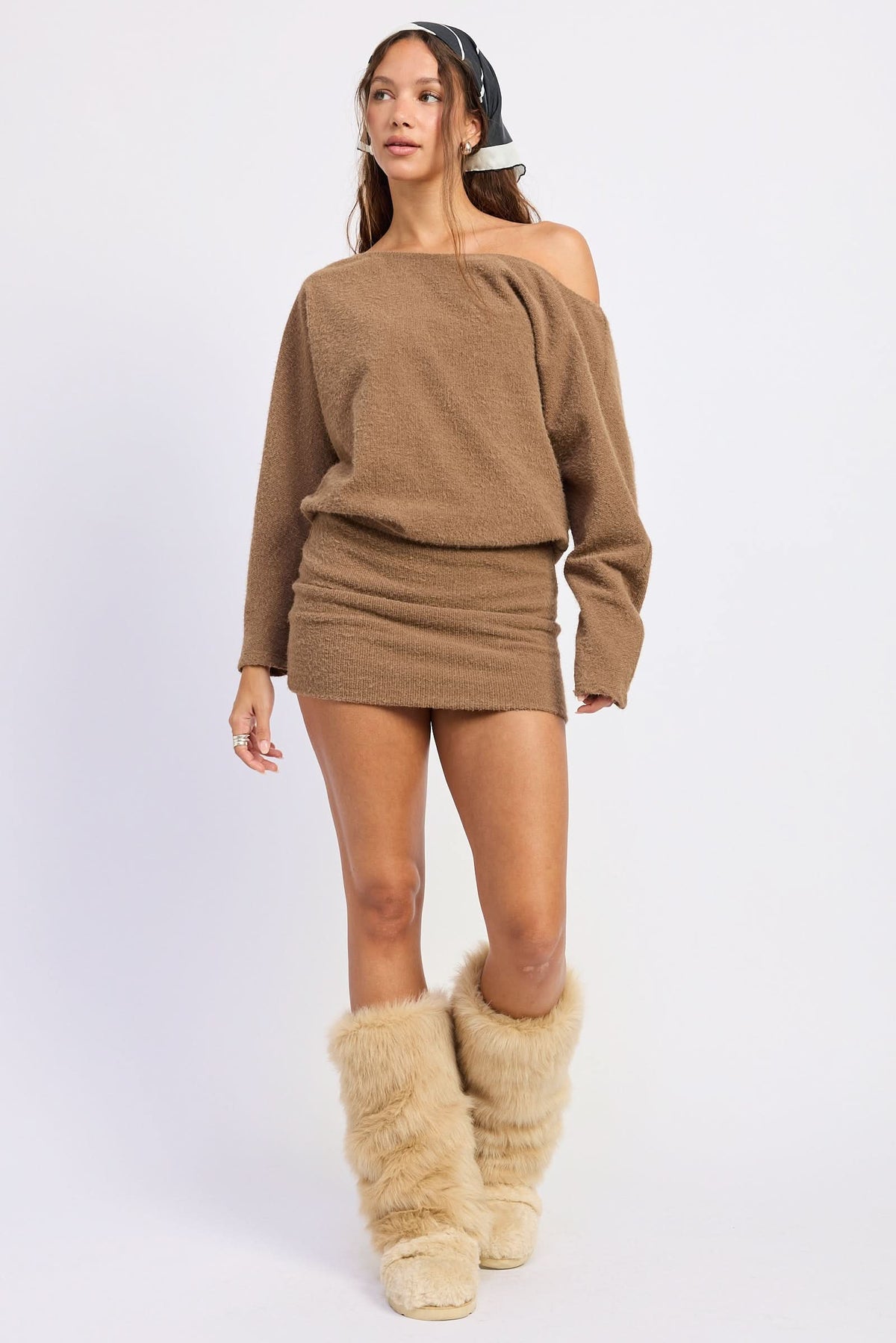 Woman wearing brown long-sleeve mini dress with tall textured boots against white background.