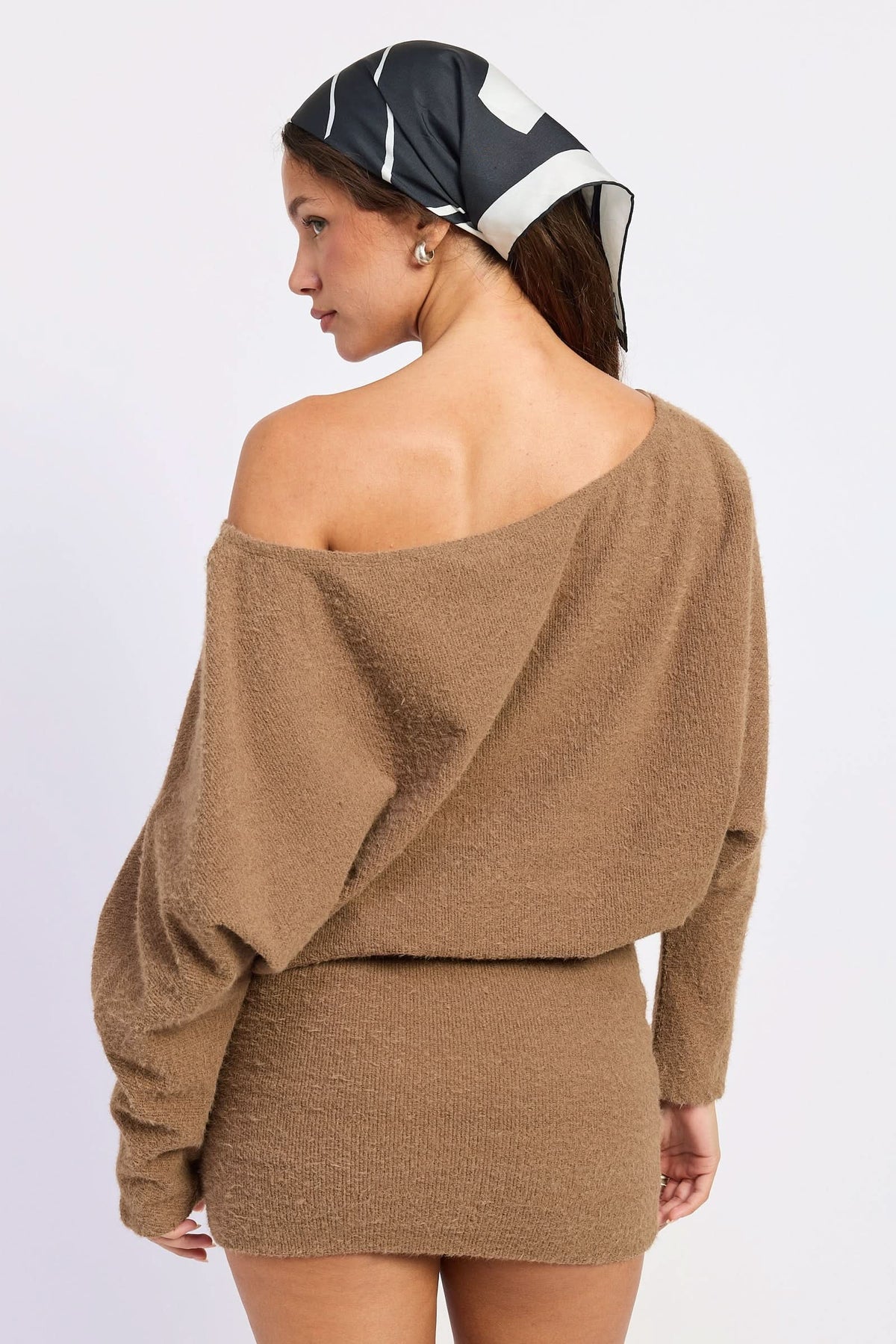 Woman wearing brown asymmetrical mini dress, back view showing draped bodice and fitted skirt against white background.
