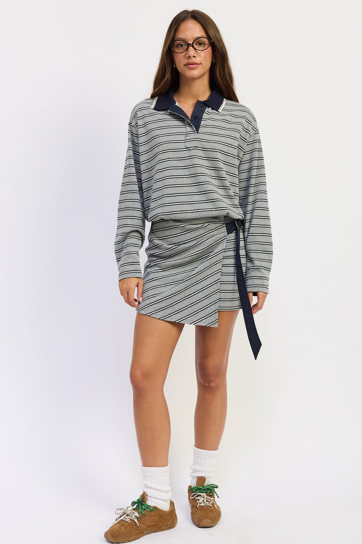 Model wearing heather grey Varsity Club Striped Polo Mini Dress with navy stripes, contrasting collar and wrap-style mini skirt.