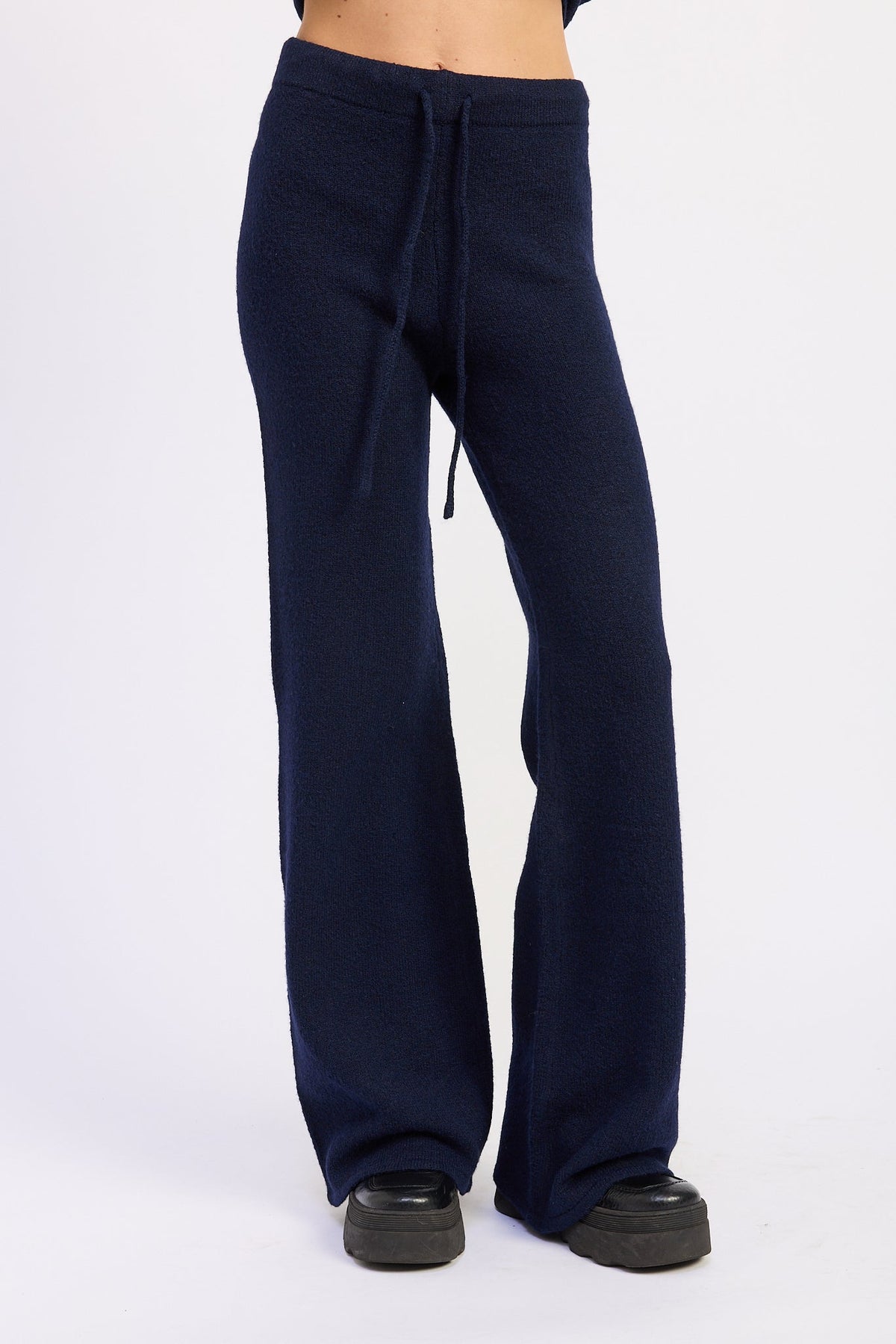 Front detail of navy knit pants with adjustable drawstring waist and relaxed wide legs.
