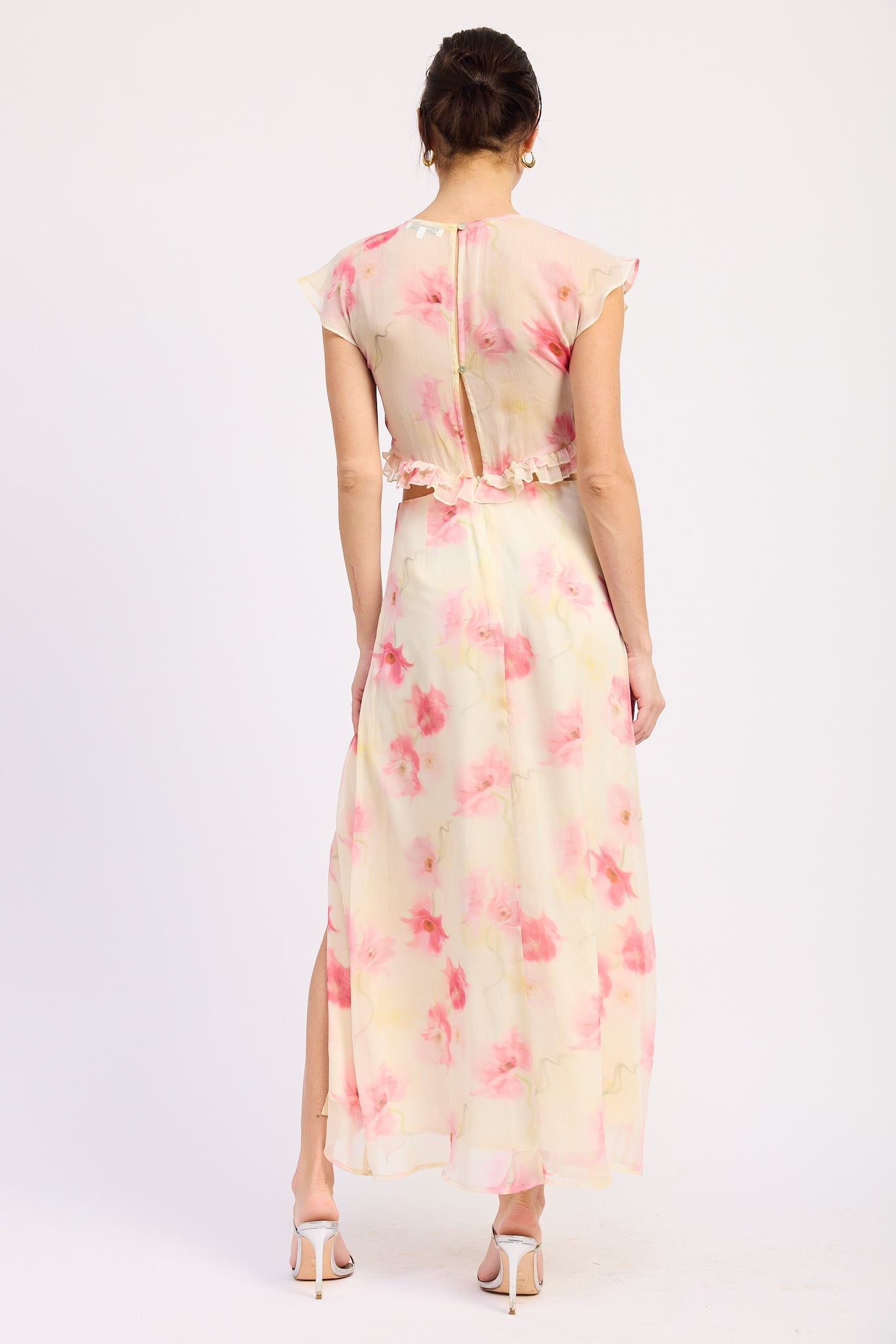 Back view of ivory and pink floral ruffle maxi dress with V neckline, flutter sleeves, waist cutouts and front slit